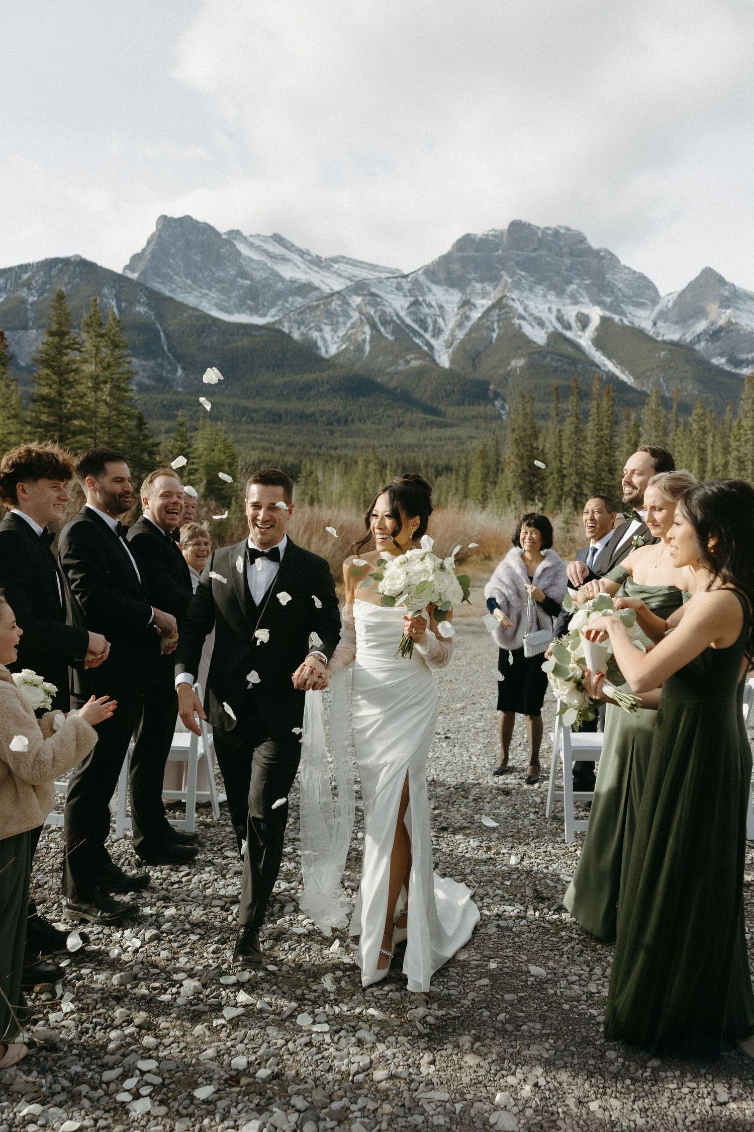 Wedding party celebrates with champagne toasts against dramatic mountain backdrop in rocky outdoor setting.