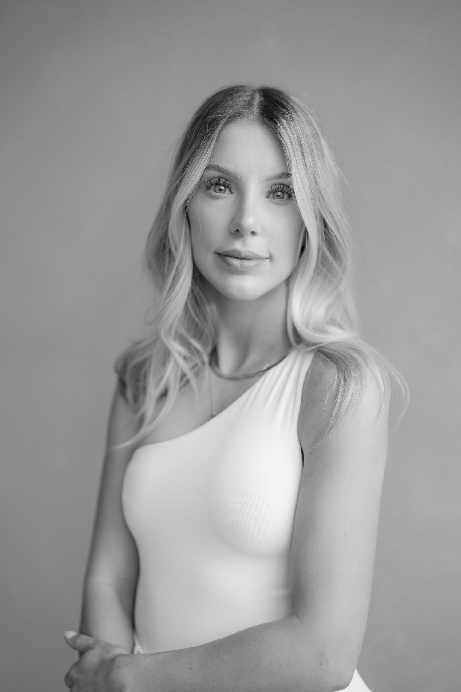 A series of black and white artistic portraits showing a person with blonde hair in a white top against a neutral background.