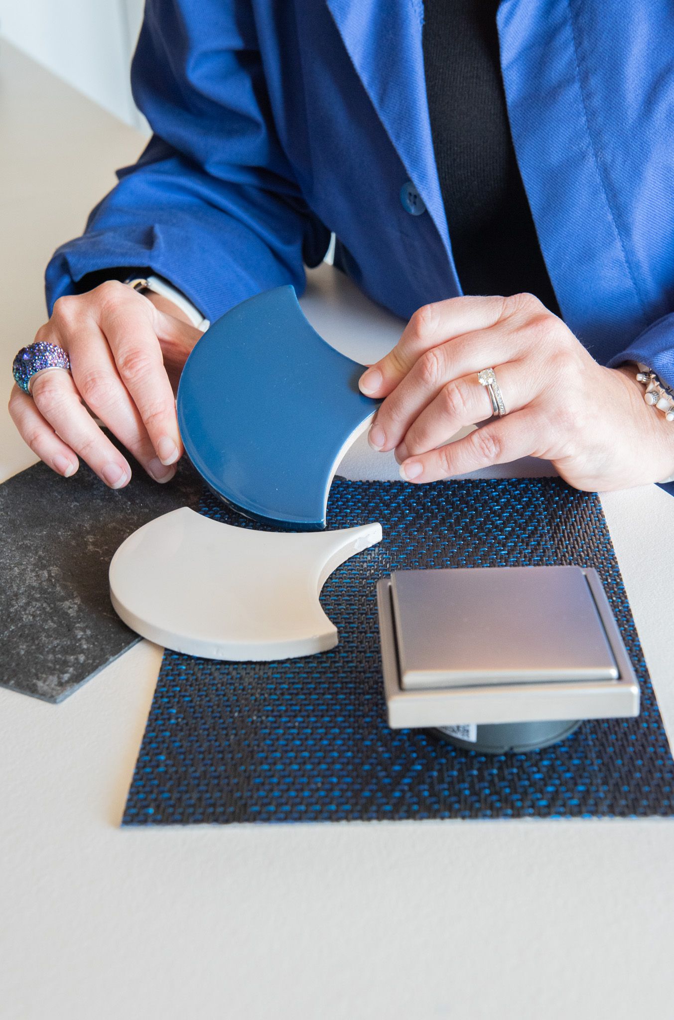 Une décoratrice d'intérieur examine des échantillons de céramique bleue et blanche, ainsi que des échantillons de textiles foncés et de fini