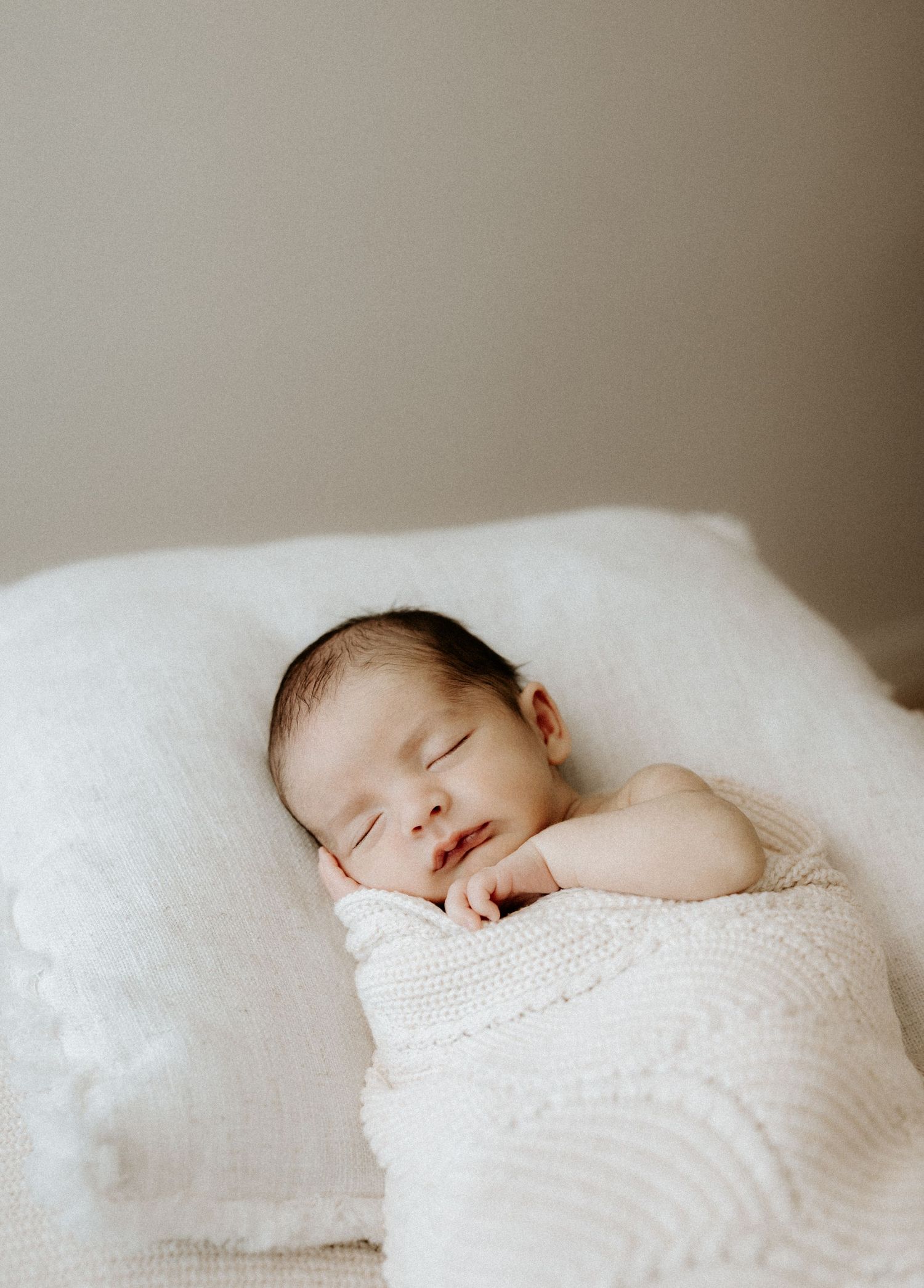 Newborn captured at an in home session with neutral tones.