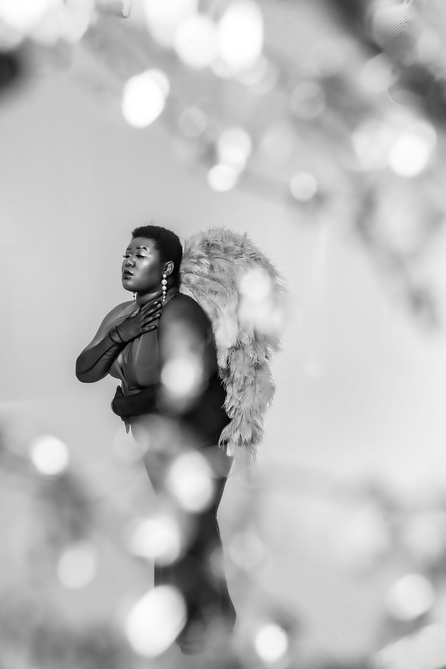 Black & white photo Black plus size woman with short hair in long gloves and a dress with angel wings. Empowerment session by Hinton Imagery