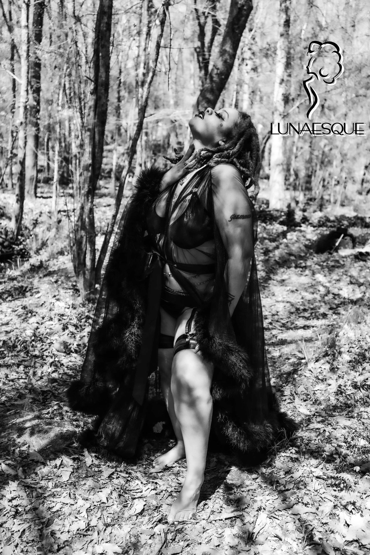 Black and white image of a Black woman with locs in a luxury robe. she is looking up towards the sky touching her neck. Jacksonville NC