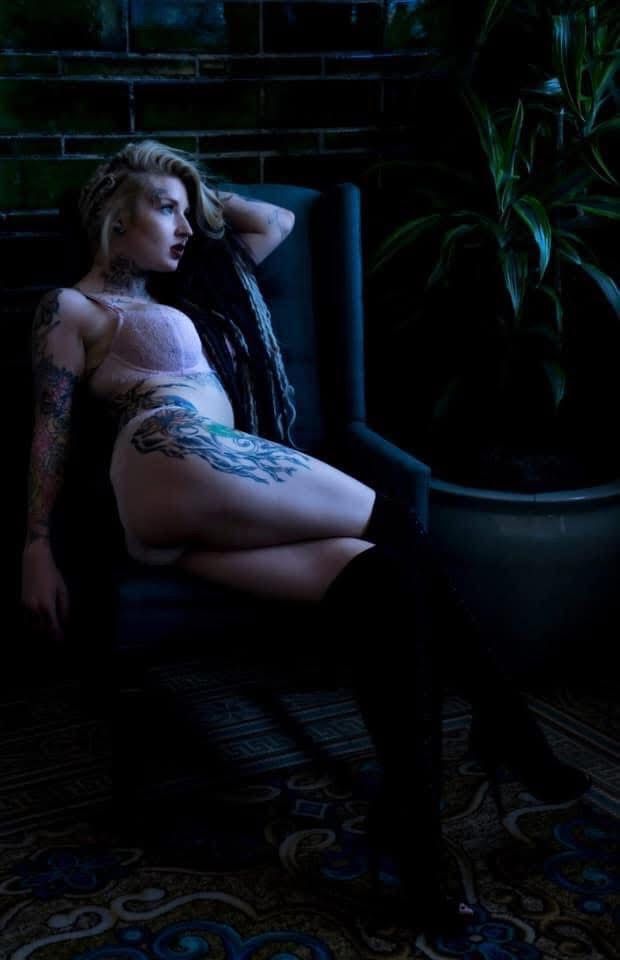 Moody image of white woman with dreads sitting in a chair tattoos prominent. Boudoir Portrait session with Hinton Imagery