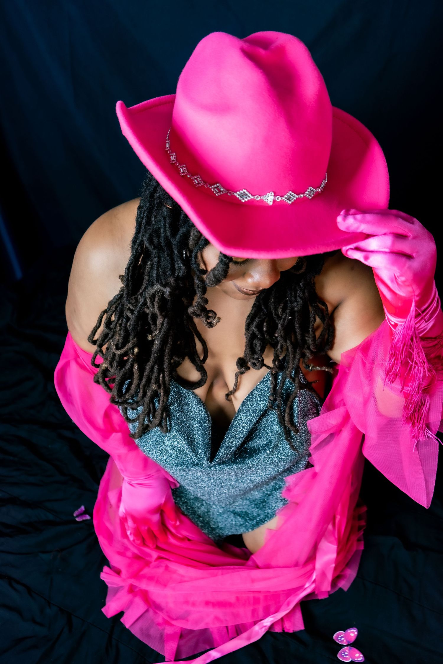 Beautiful Black woman with locs in a Pink Cowboy Hat and long tasseled pink gloves and a luxury pink robe. Boudoir Session by Hinton Imagery
