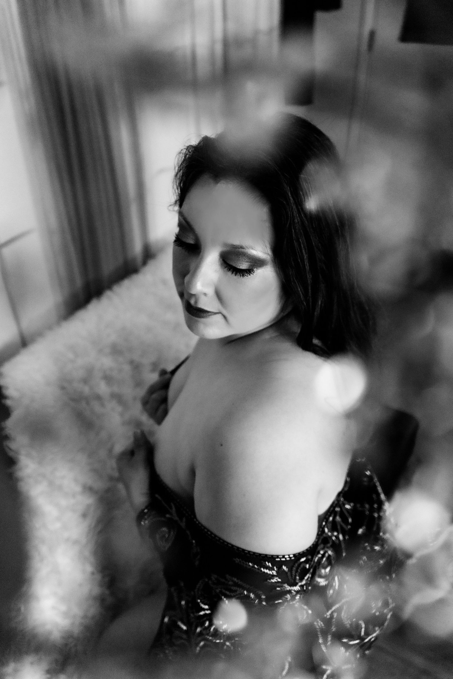 Boudoir portrait session by Hinton Imagery Jacksonville NC. Black & White image Latina woman looking over her shoulder with fabric draped
