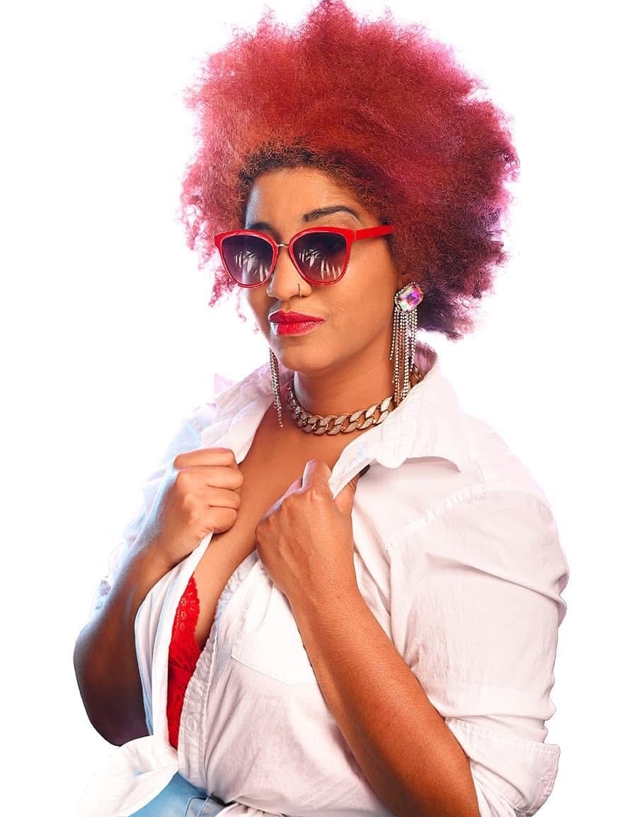 Image of Hinton the photographer behind Hinton imagery, she has a huge red afro here and is wearing red sunglasses Jacksonville NC
