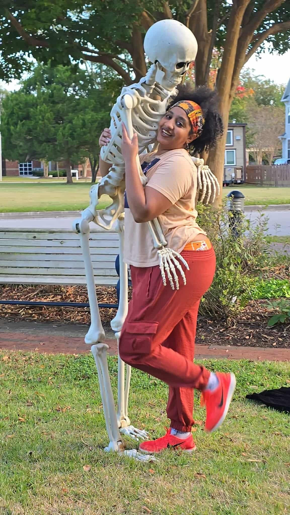 Candid Image of Hinton the Boudoir & Intimate Portrait Photographer in Jacksonville NC being playful & dancing with a large skeleton