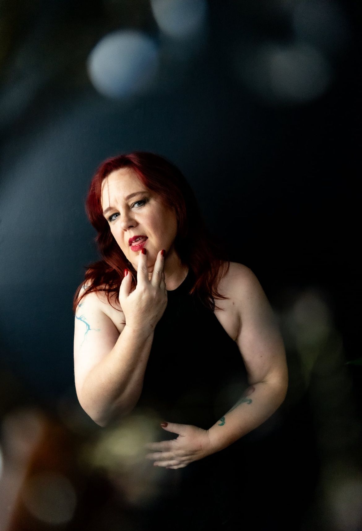 Boudoir portrait session by Hinton Imagery Gorgeous white woman at an Empowerment session hands up to her lip looking directly at camera.
