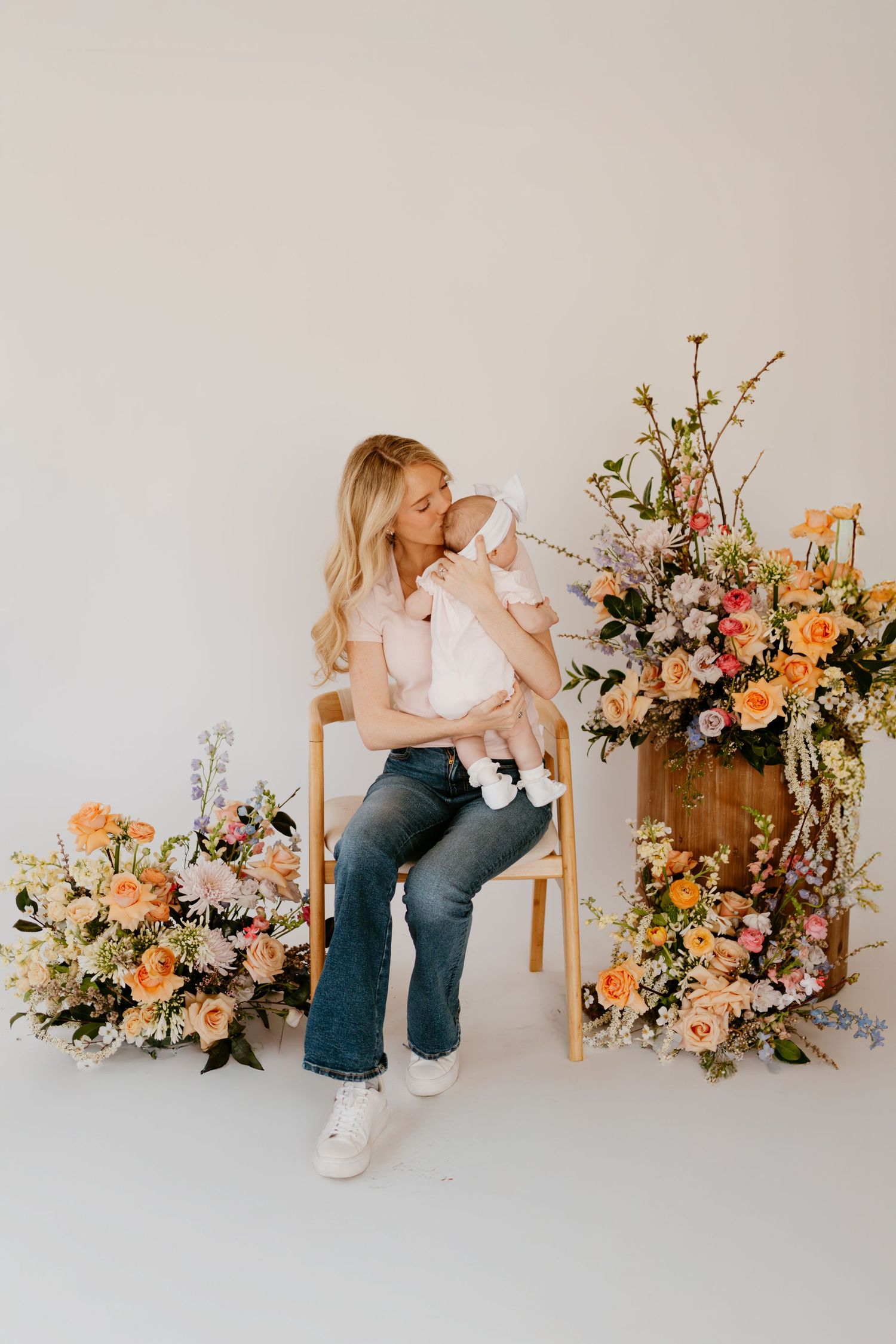 Family photoshoot with elegant floral arrangements featuring pink and peach blooms against white backdrop.