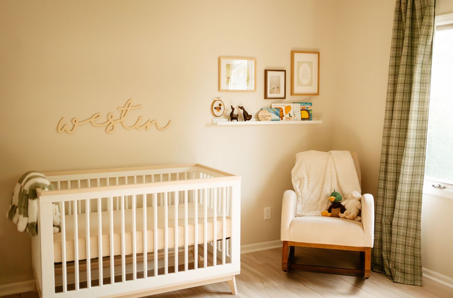 Neutral nursery room with white crib, name sign reading Weston, rocking chair, and plaid curtains.