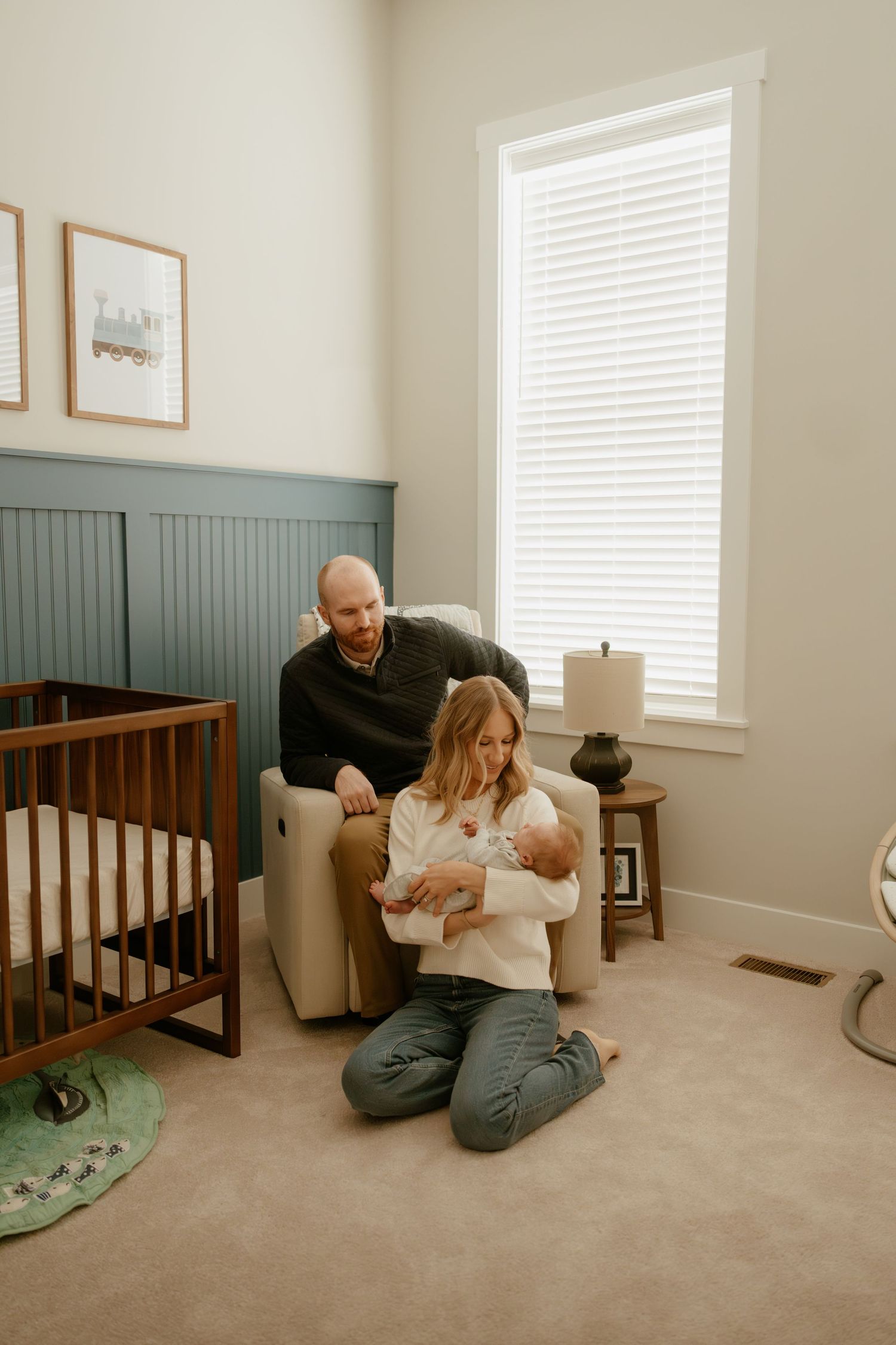 Candid family moments photographed in a cozy nursery room with natural window light.