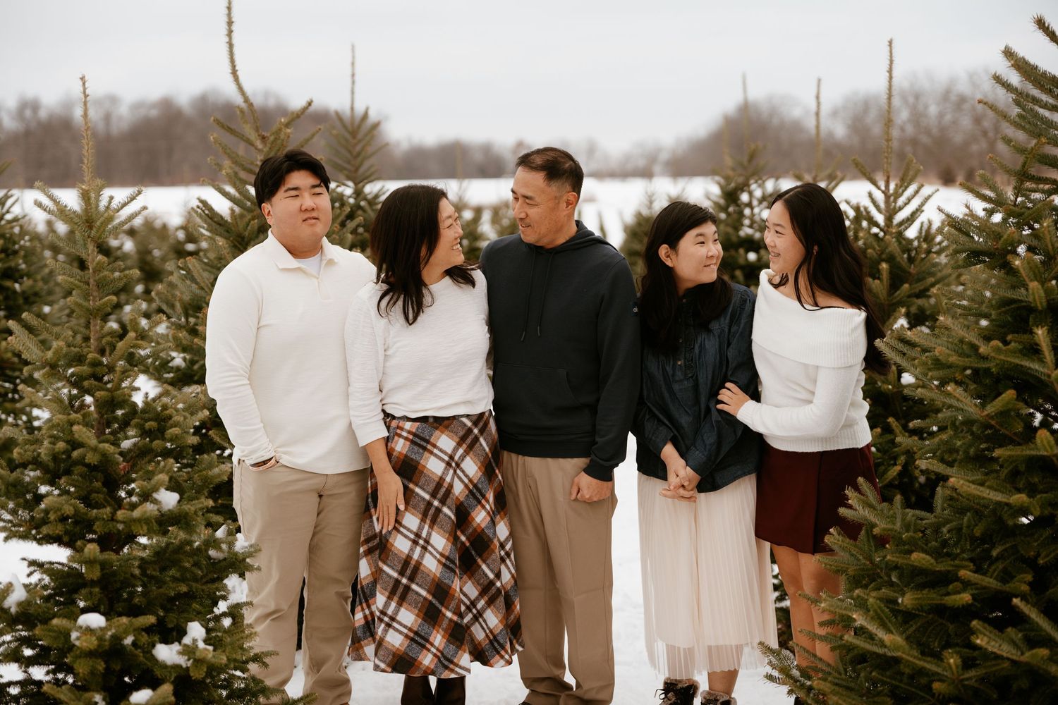 Group photo among snow-covered evergreen trees at a Christmas tree farm in winter.