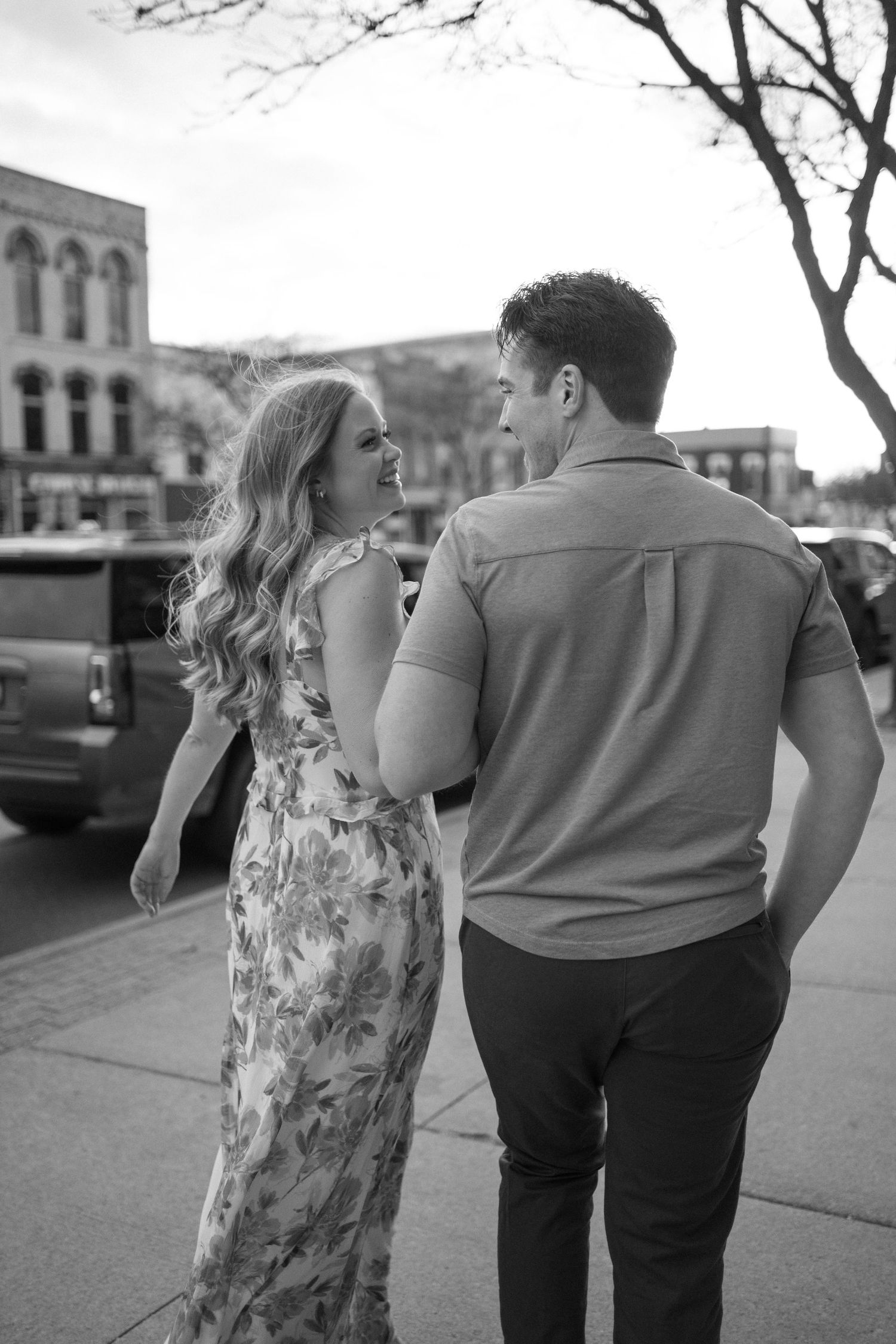 Black and white street photography of a couple walking together in an urban setting.