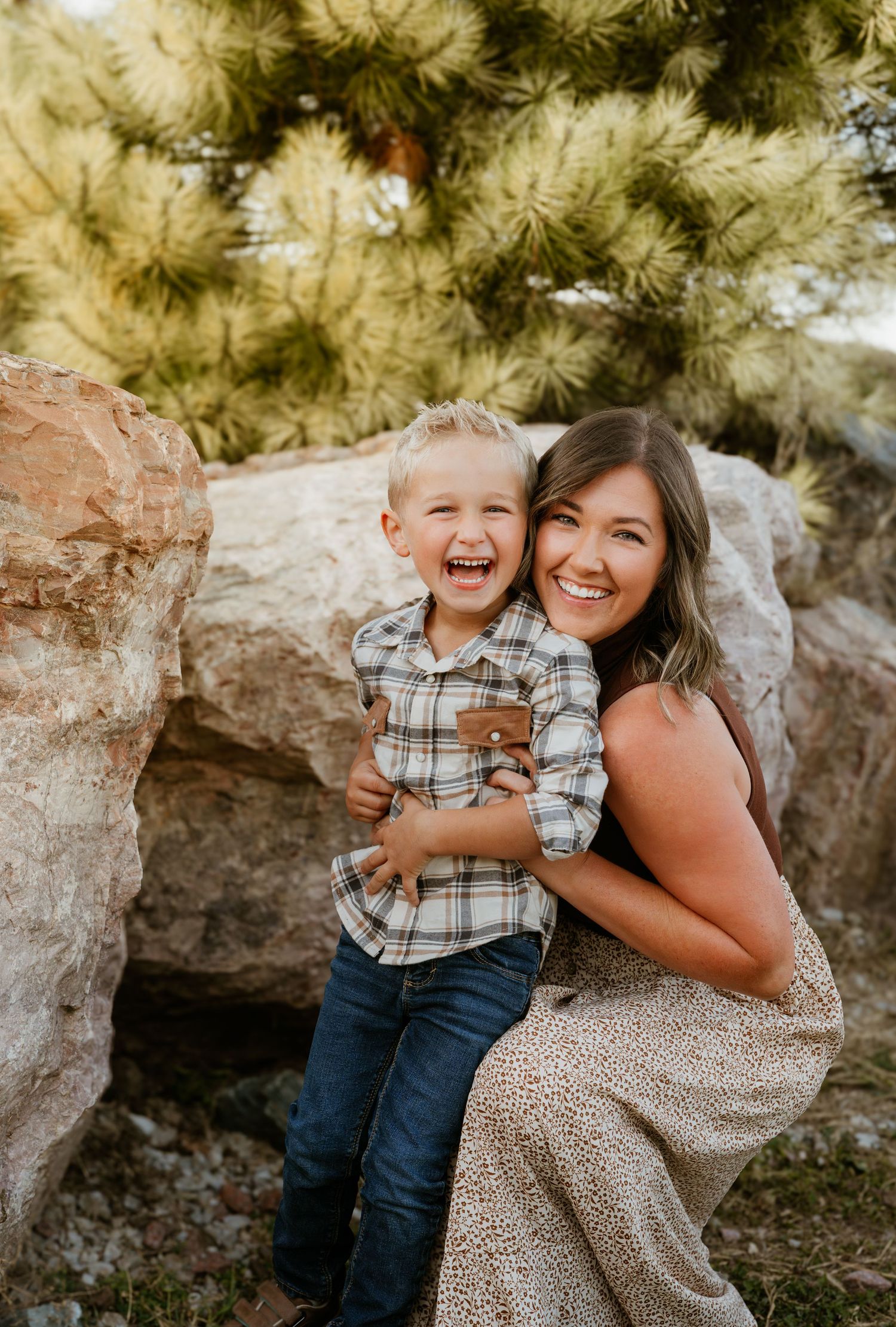 Joyful outdoor family portrait session against rocky backdrop in natural lighting.