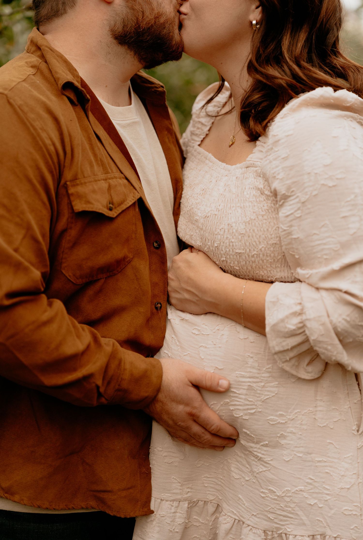 Intimate moment between couple in autumn clothing during maternity photo shoot.