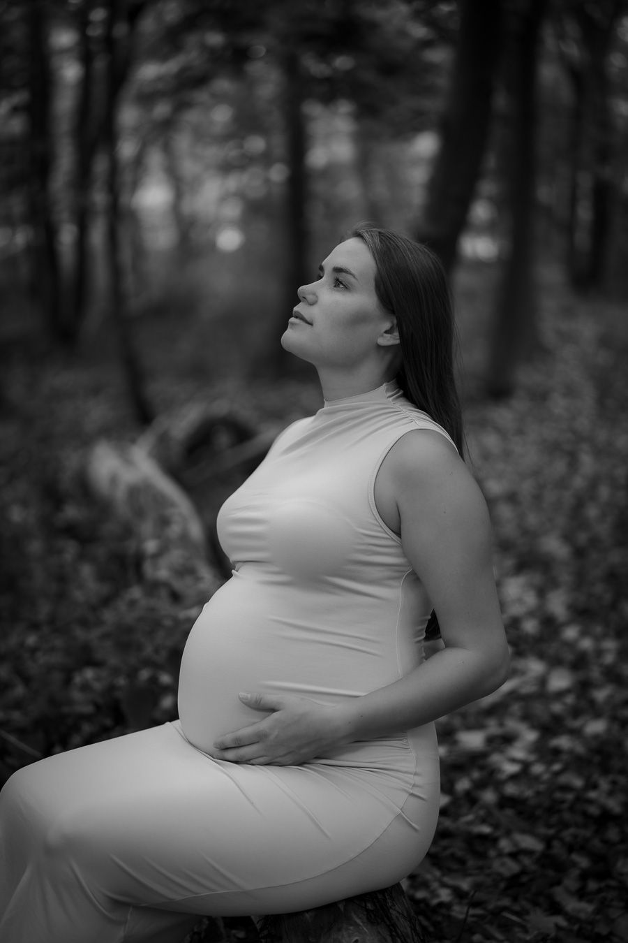 Black and white portrait of person in white dress outdoors among trees.