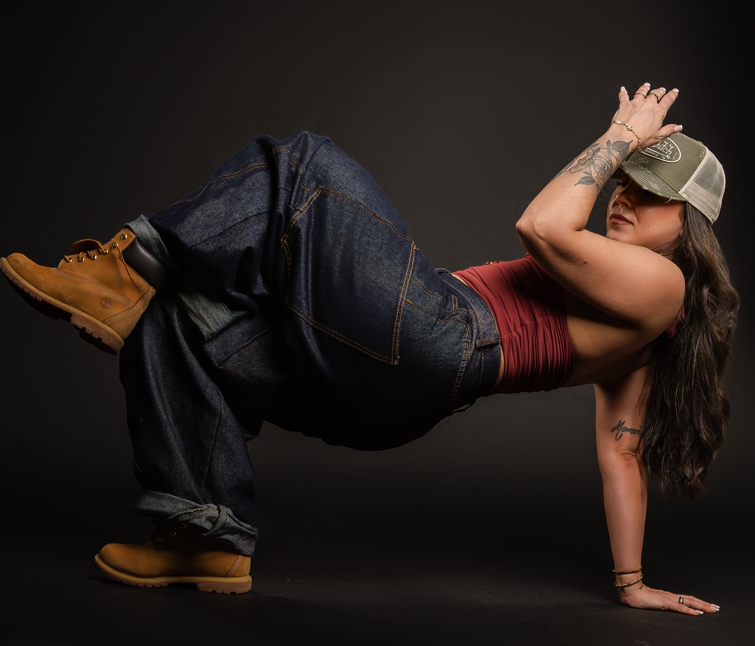 Dancer performs breakdancing freeze move in casual wear against dark background.