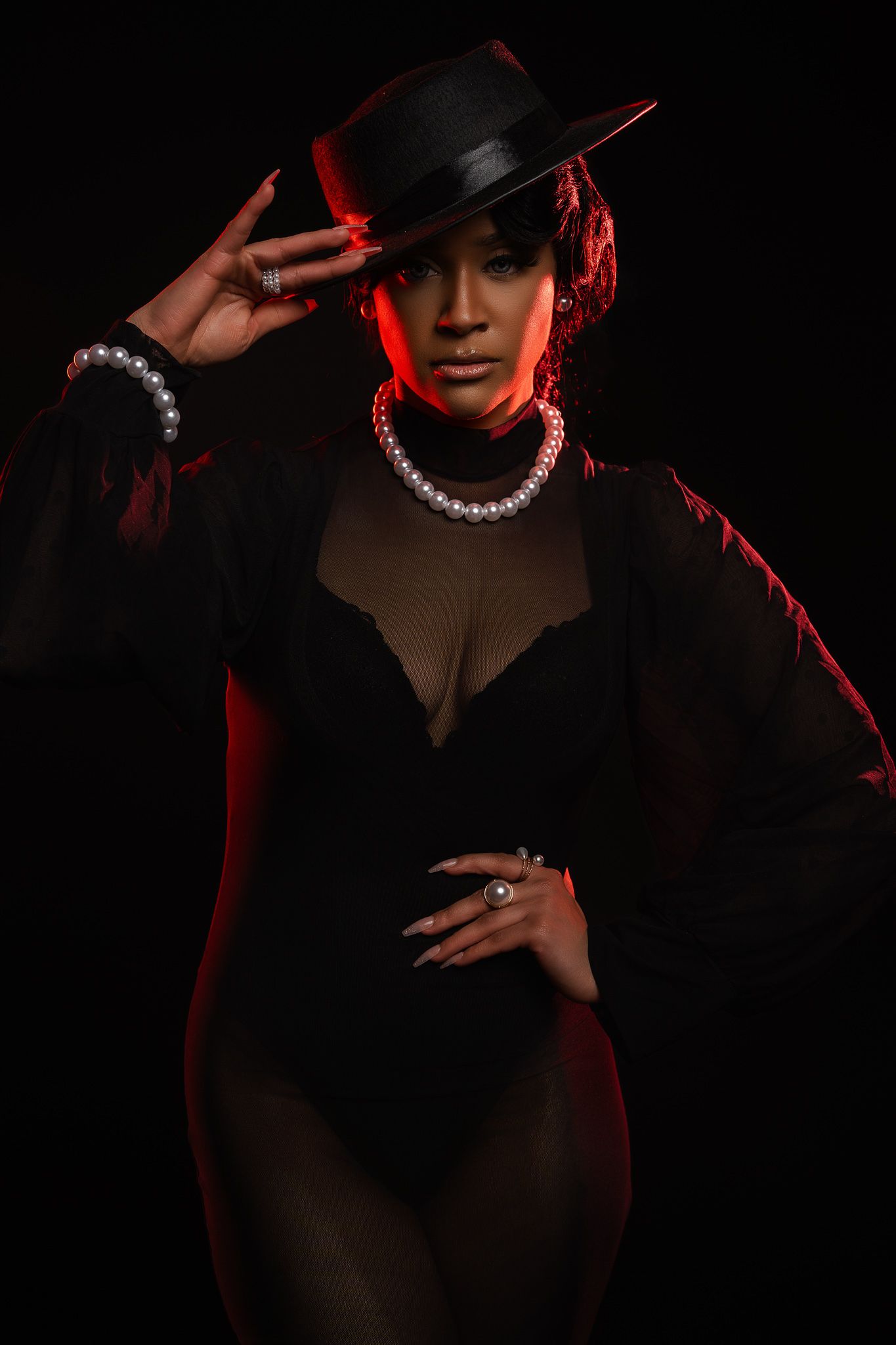 Dramatic noir-style portrait series in black with red lighting showing figure in hat and pearl necklace against dark background.
