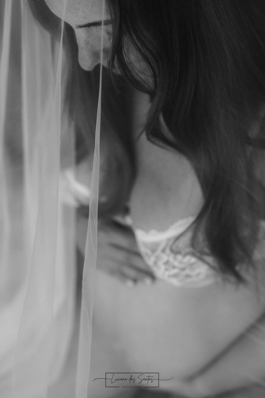 Artistic black and white boudoir photo with soft window light and flowing fabric.