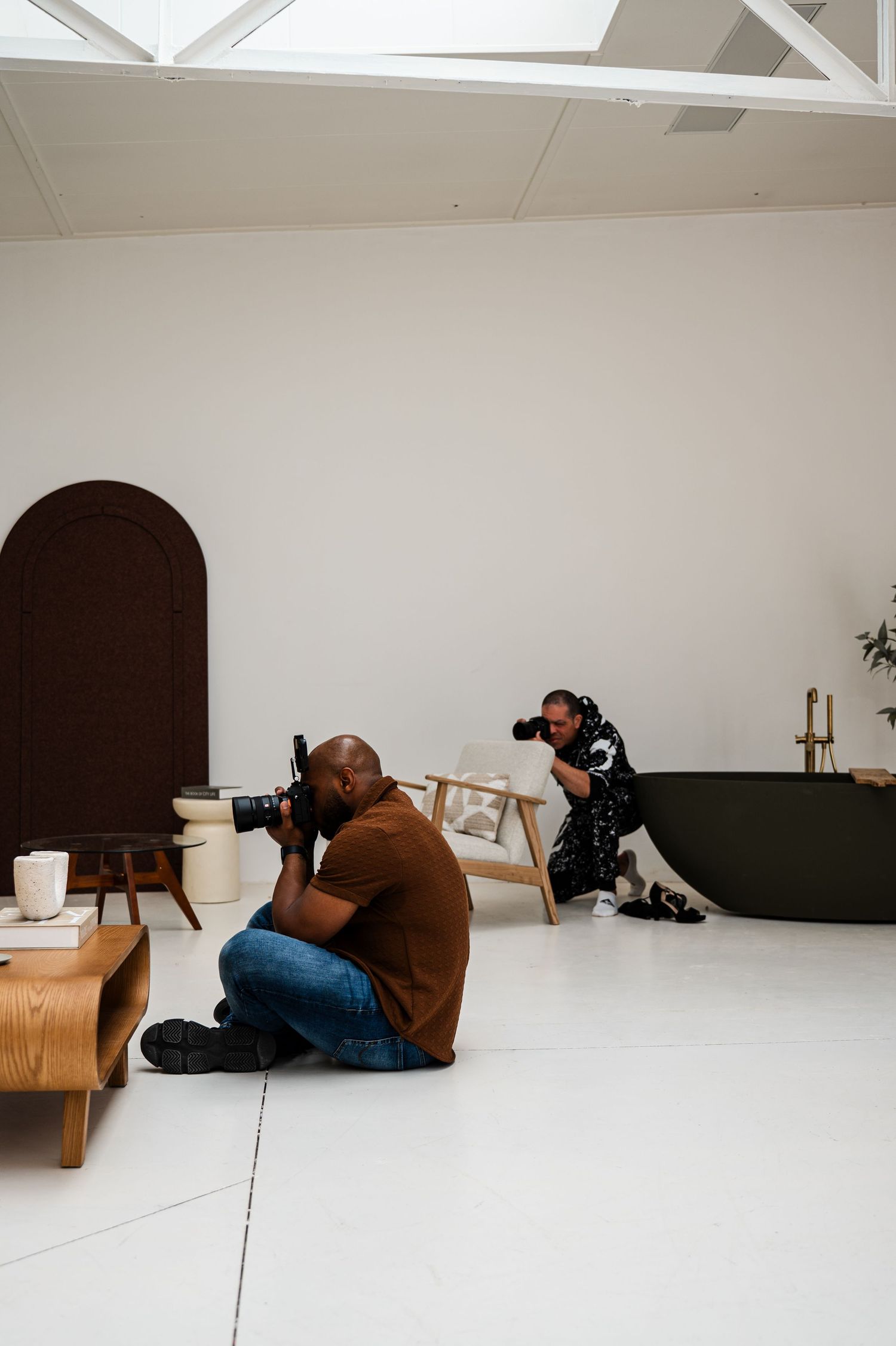 A sequence of artistic photos showing a person lying down on a white floor next to minimal furniture in a bright studio space.