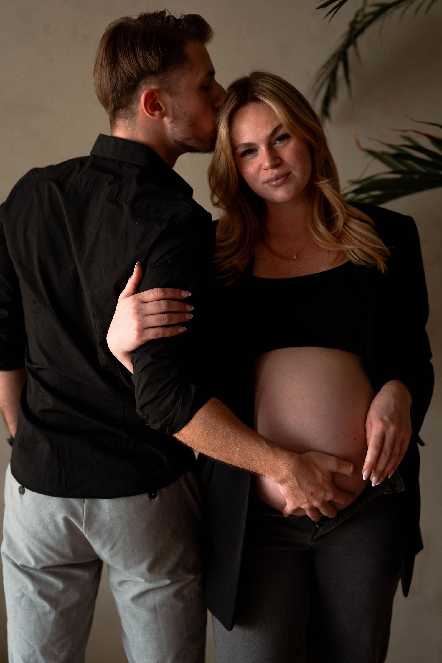 Intimate maternity photography sequence in dark tones.