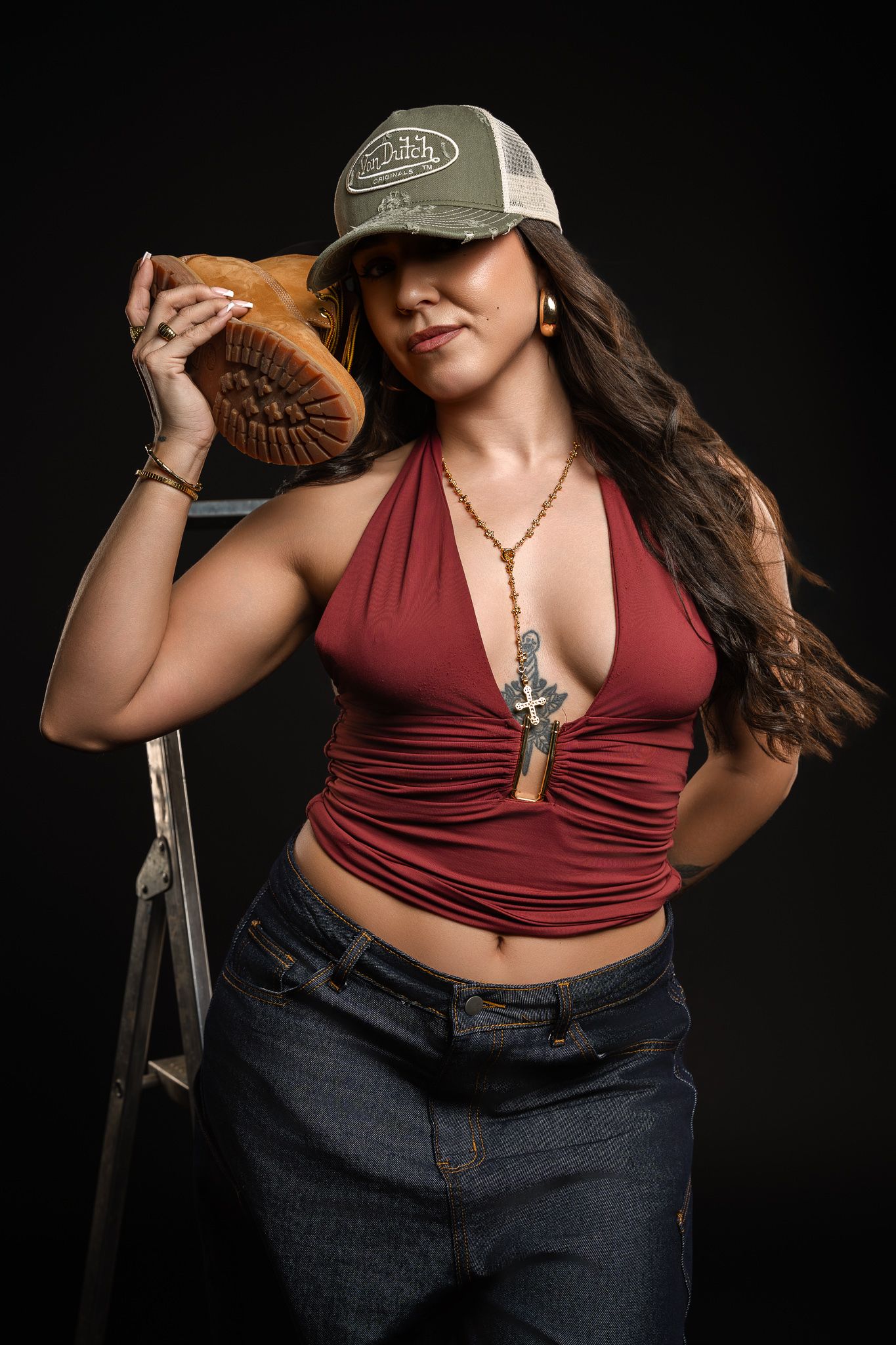 Person in burgundy crop top and jeans poses against dark background in stylish casual outfit series.