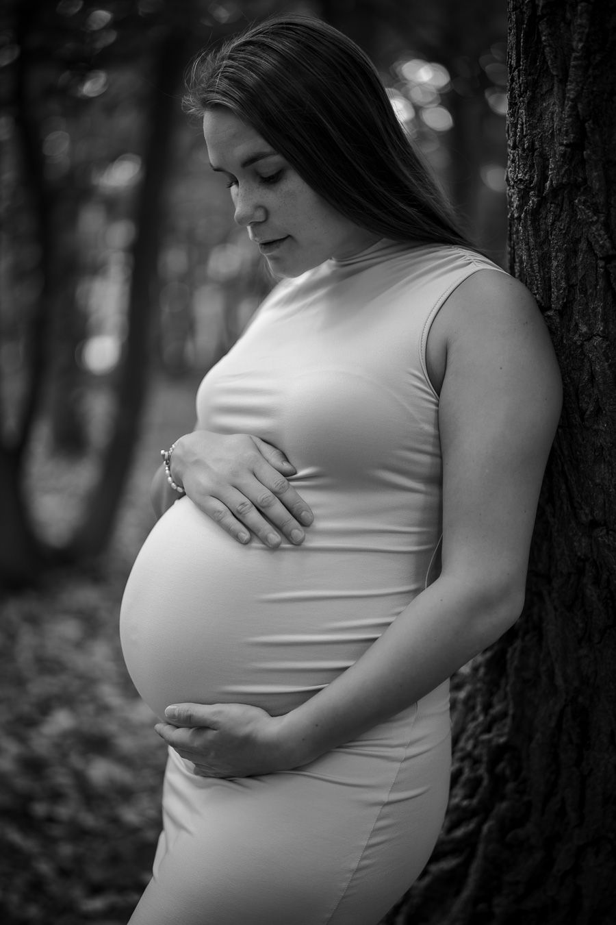Black and white maternity photos showing a pregnant belly against a dark background in an artistic style.