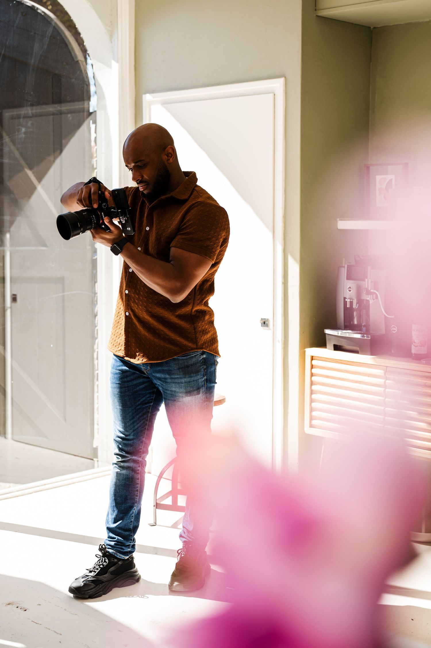 Photographer capturing artistic shots with pink light effects in bright interior space.