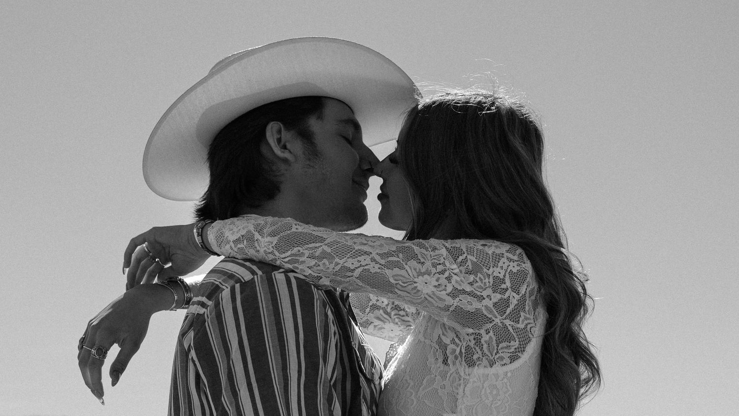 Black and white photo of couple sharing a kiss, one wearing a white cowboy hat.