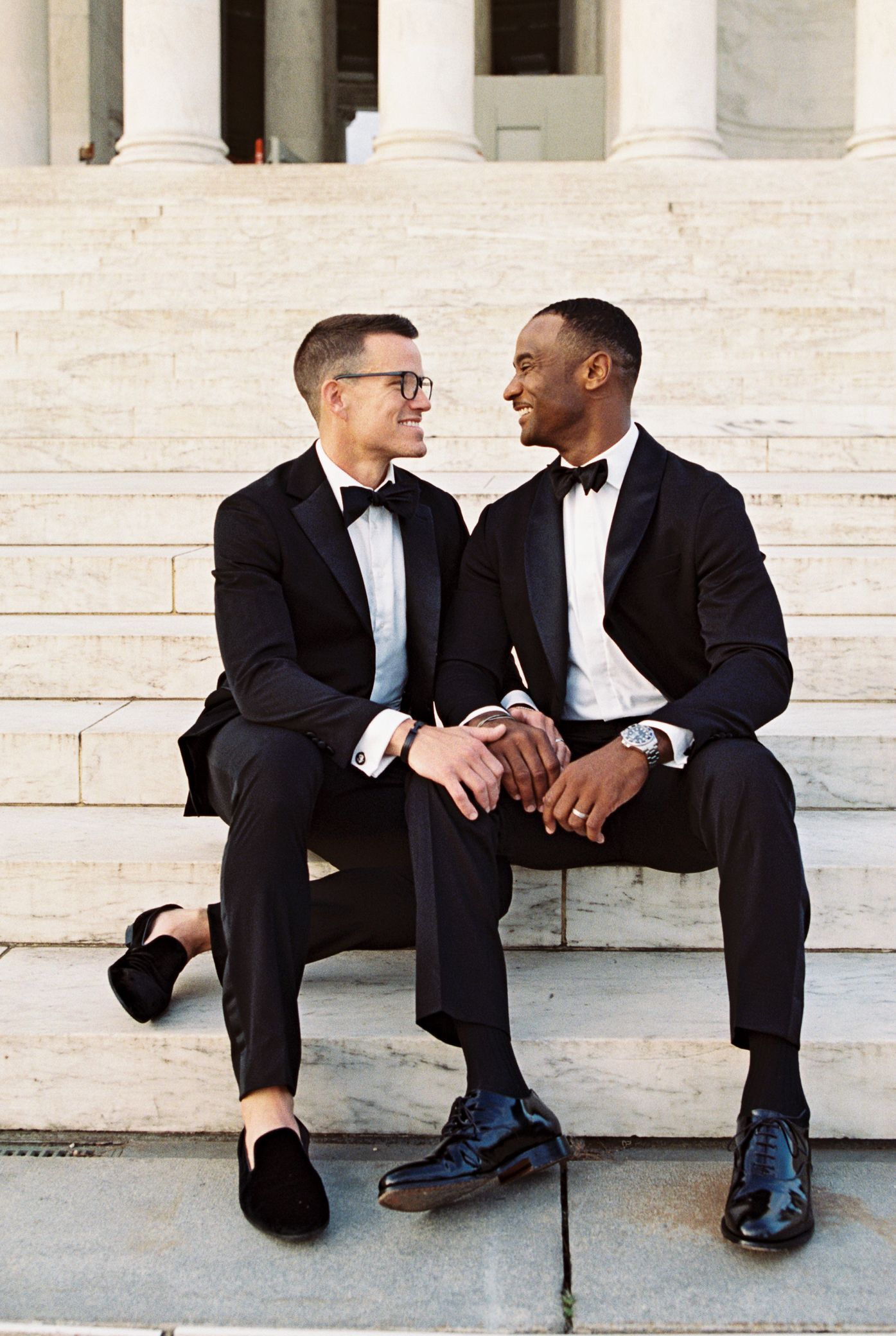 Interracial gay couple posing in tuxedos on the steps of Jefferson Memorial in Washington, DC