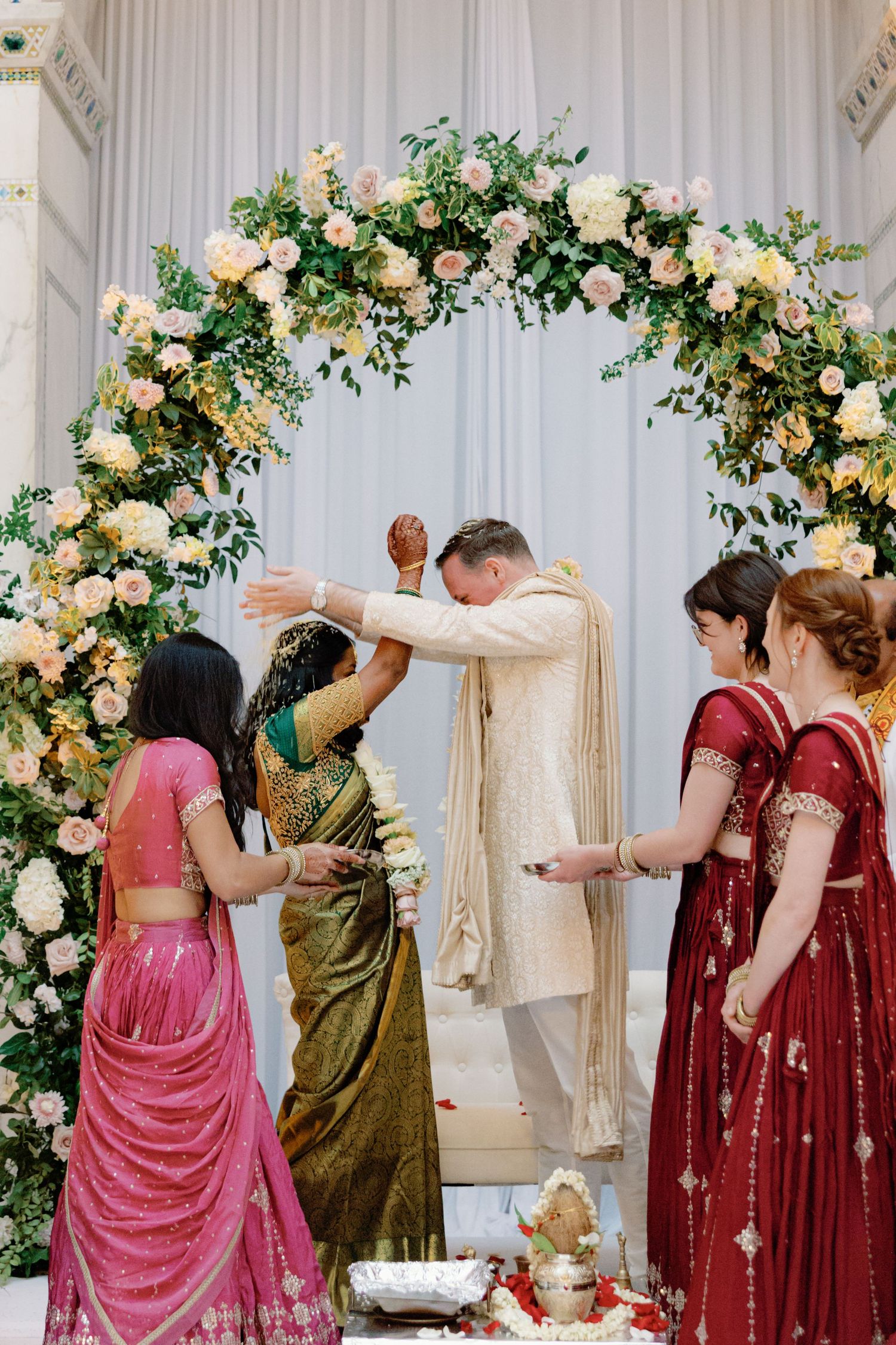 Couple showering each other with rice at their Indian wedding ceremony at Chicago Cultural Center