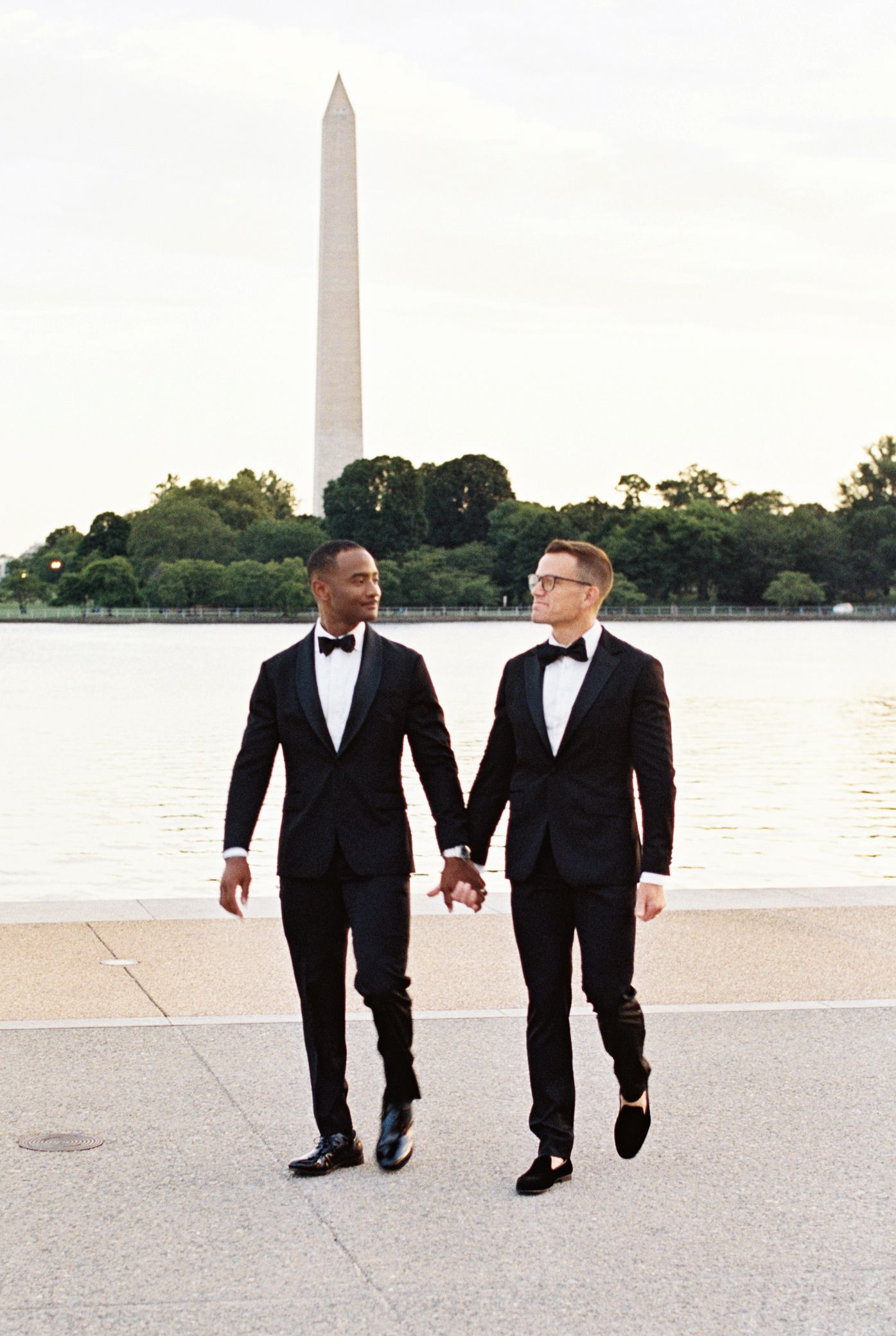 Interracial gay couple posing in tuxedos with the Washington Memorial in the background, in Washington, DC