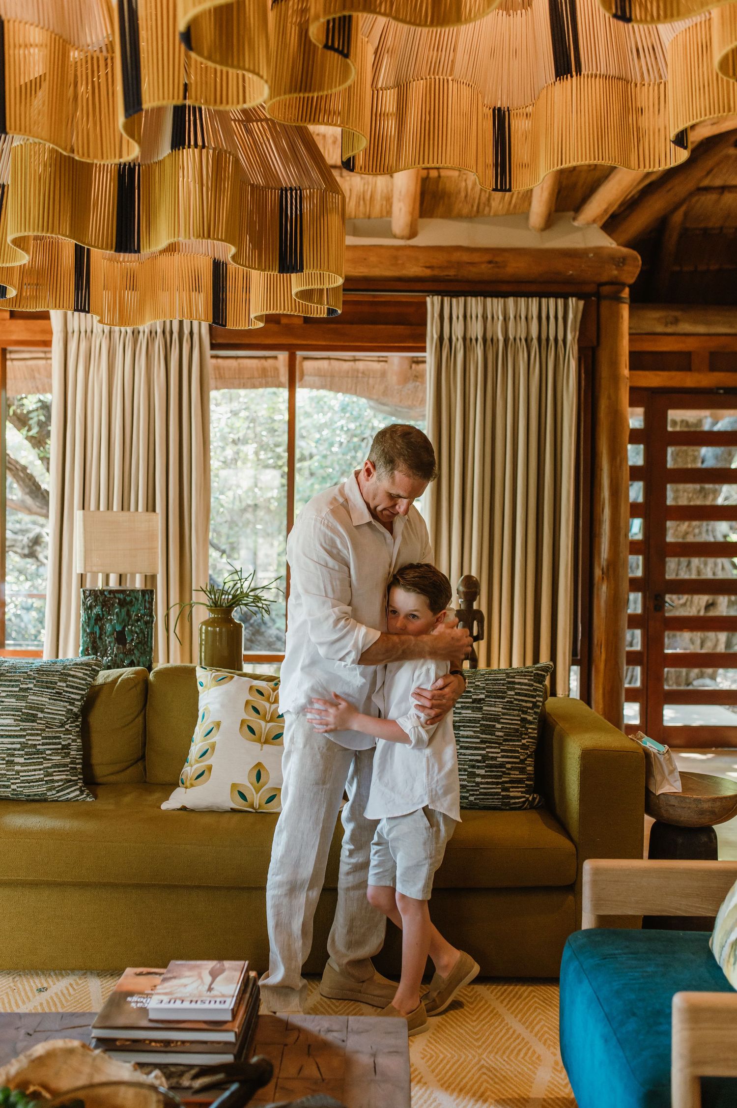 Father and son sharing a warm hug in a beautifully decorated safari lodge living room.