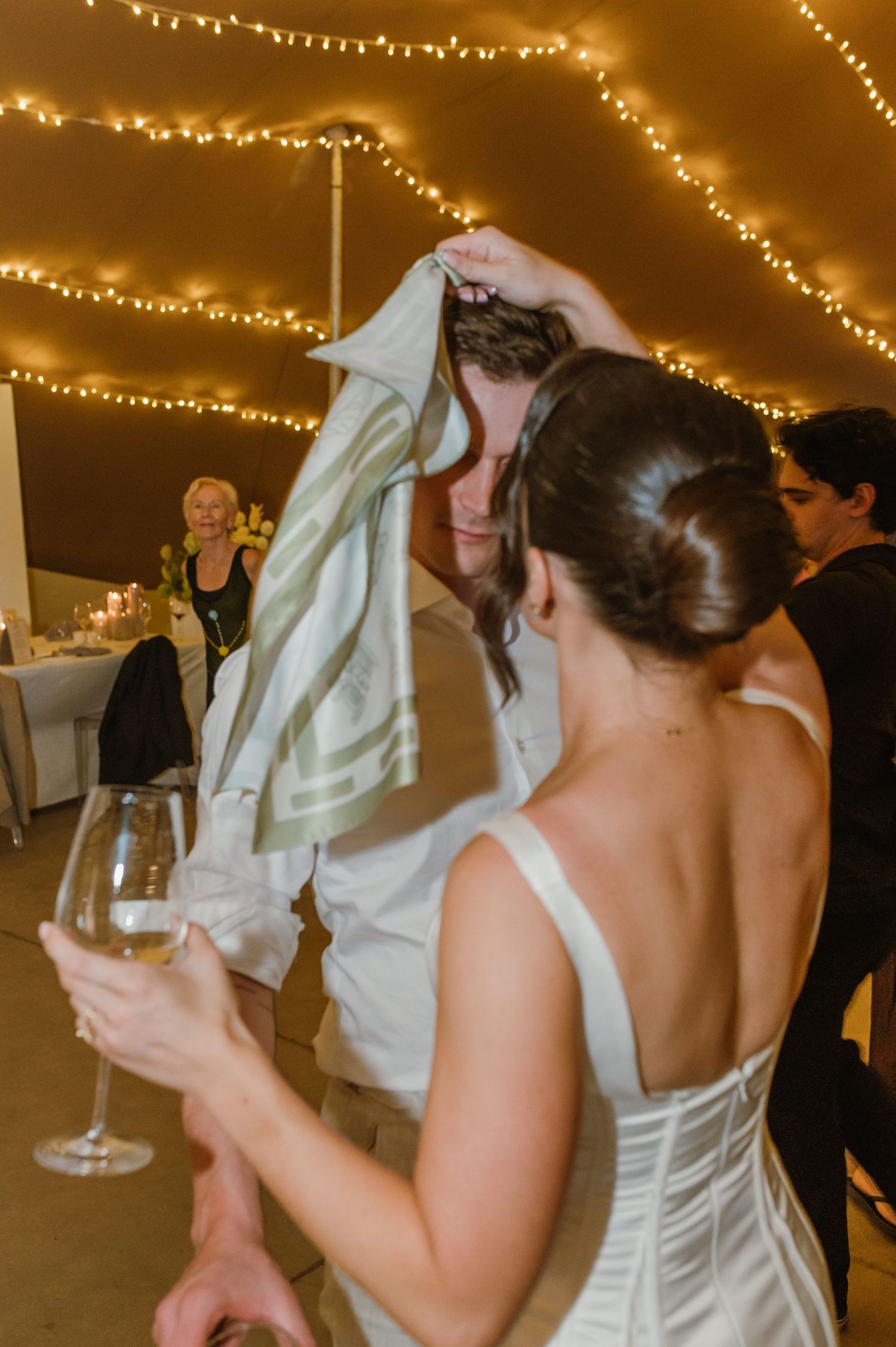Wedding guests dancing and celebrating under warm string lights.
