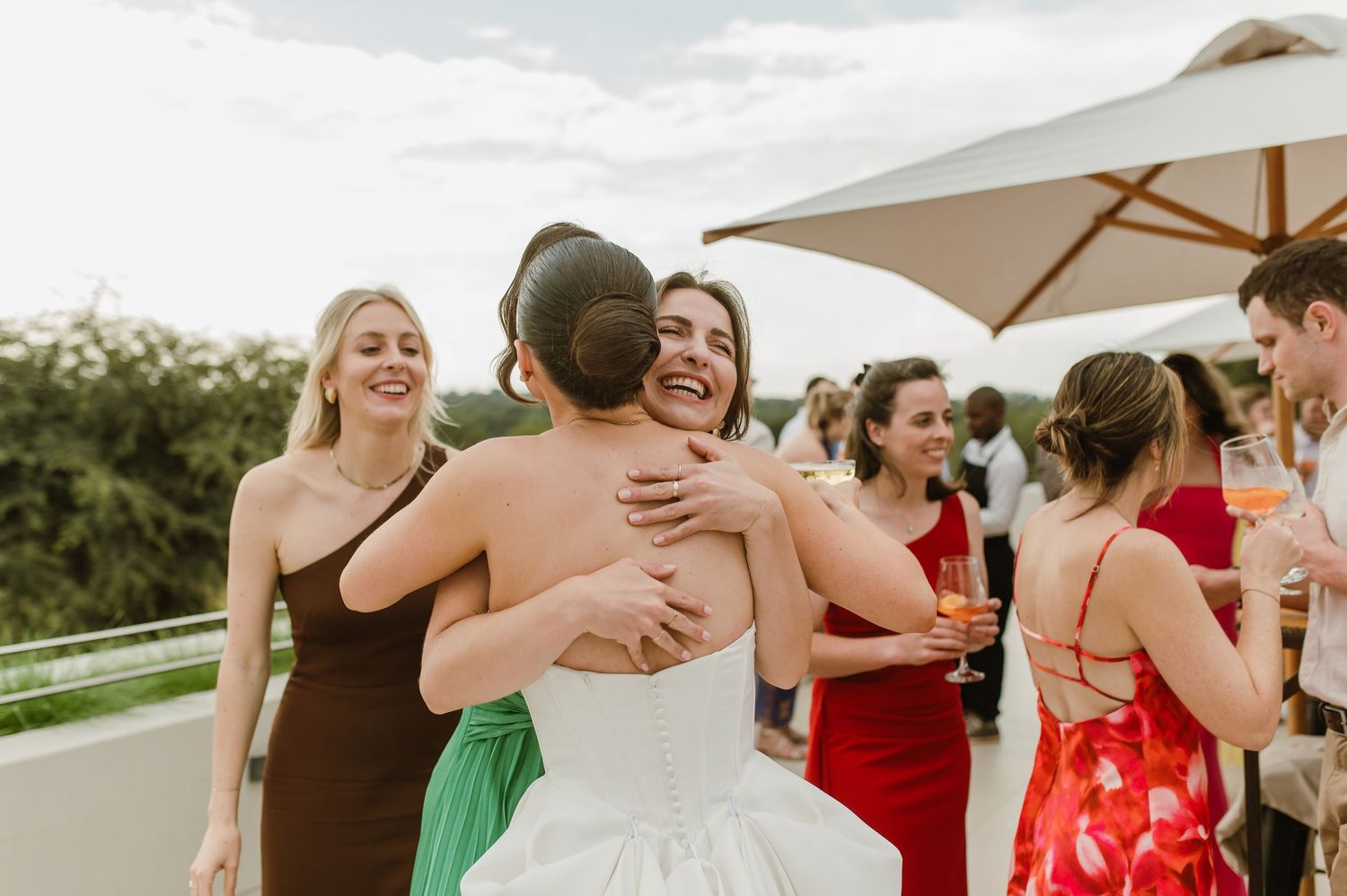 Wedding celebration on a scenic rooftop with guests hugging and mingling.