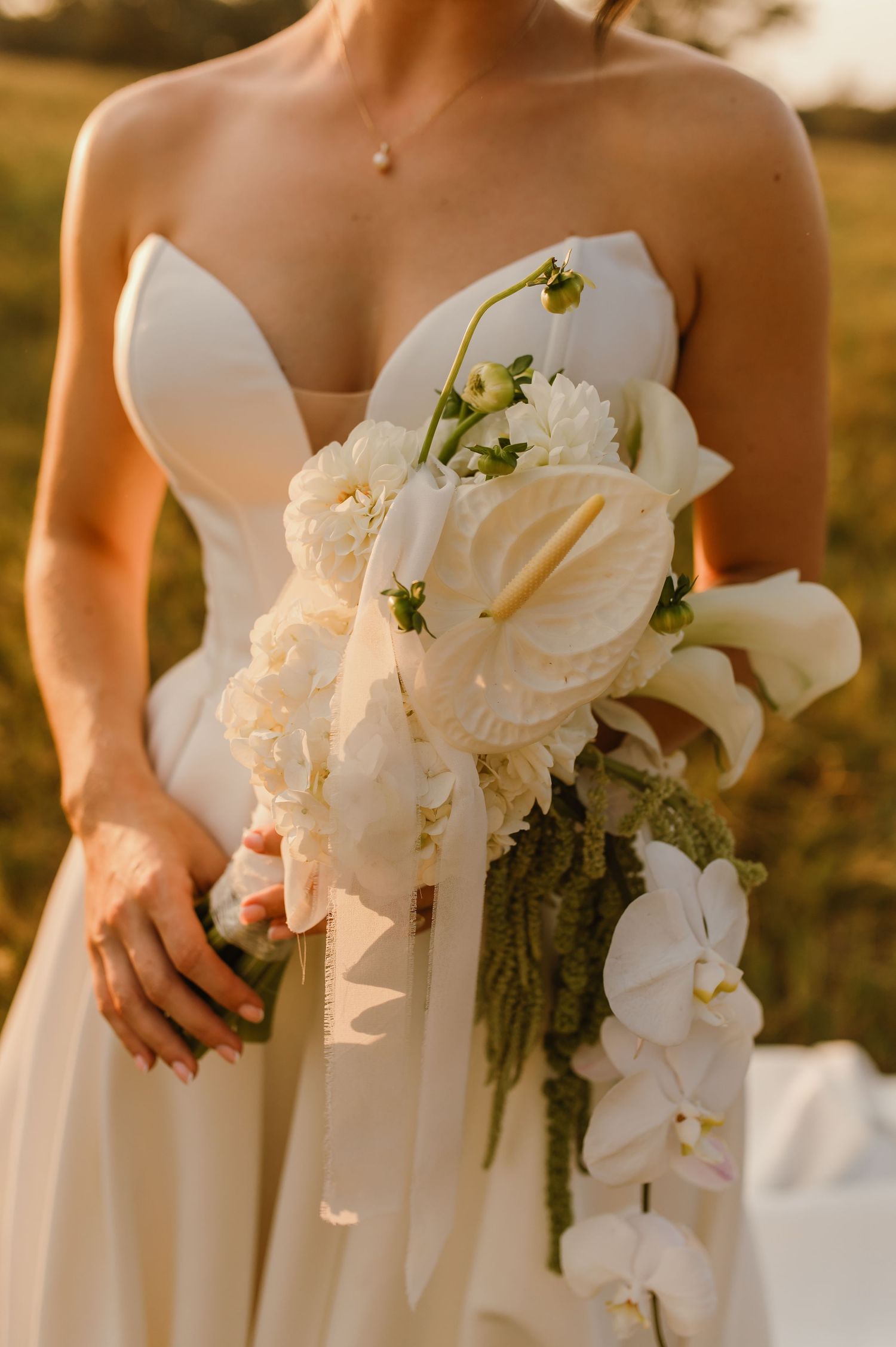 Elegant white orchid and lily bridal bouquet captured in warm sunset light.