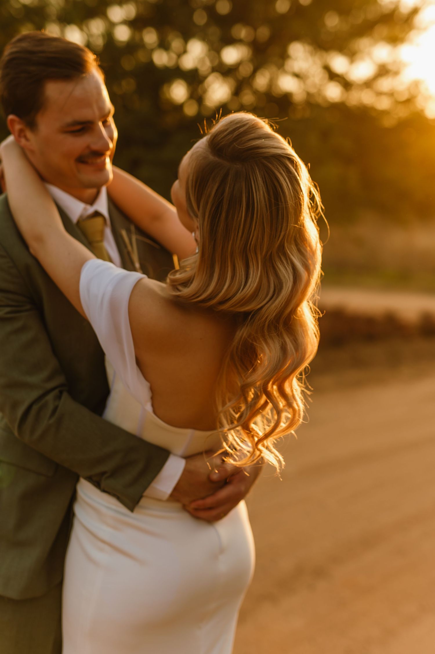A couple shares a romantic moment in warm evening light on a country path.