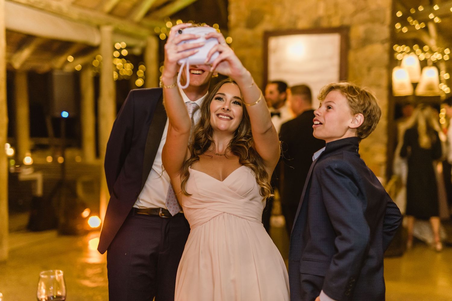 Joyful dancing moment during wedding reception in rustic venue with ambient lighting.