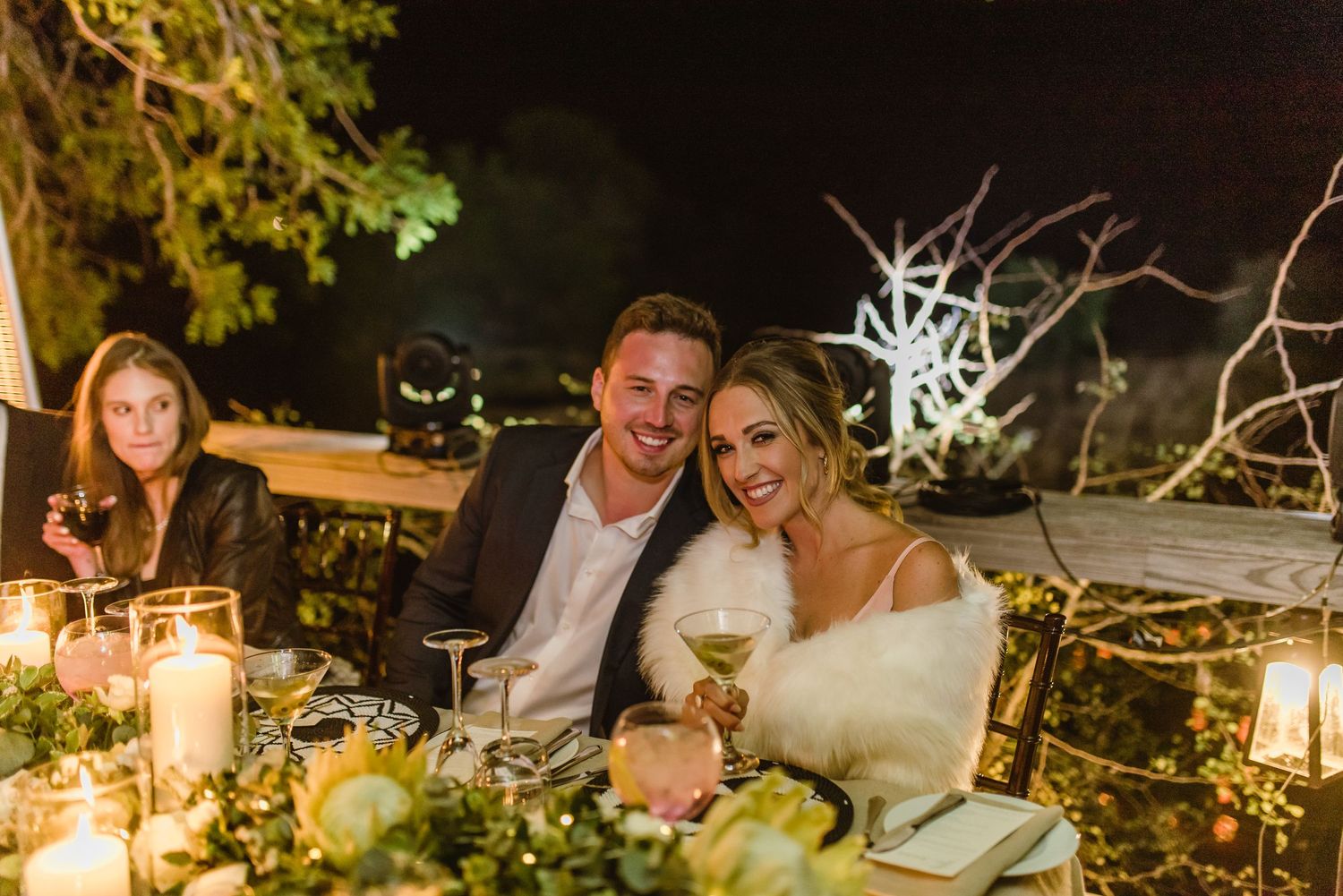 Evening wedding celebration with guests seated at beautifully decorated outdoor tables.