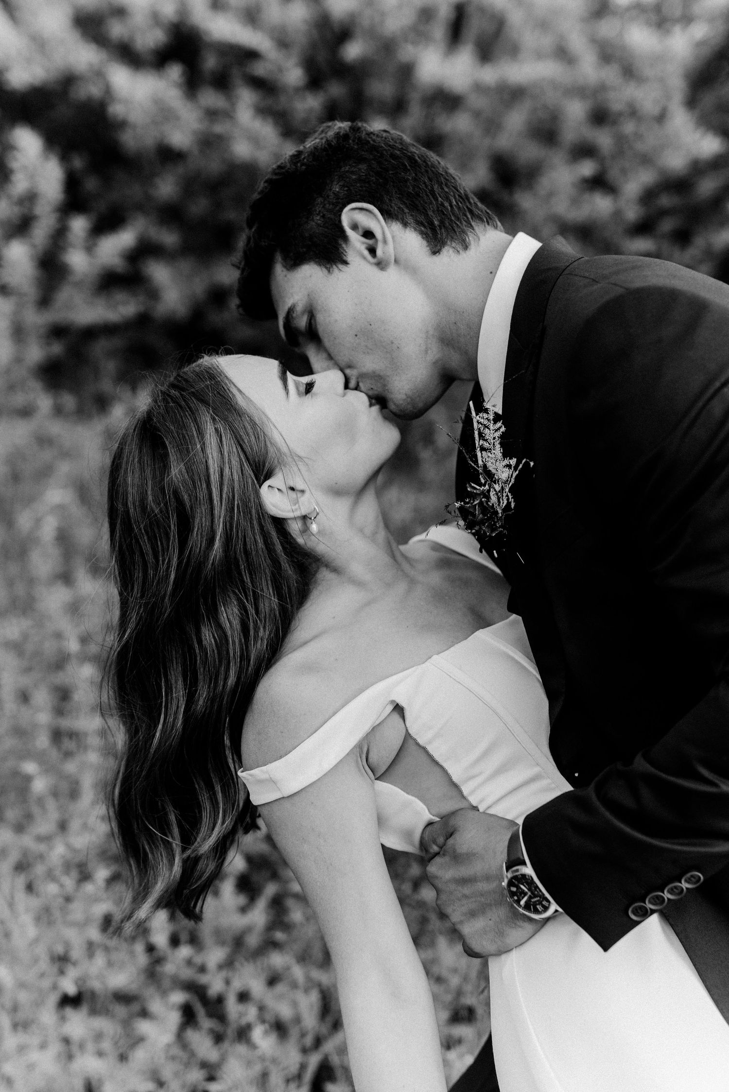 Black and white romantic wedding portrait capturing intimate kiss moment.