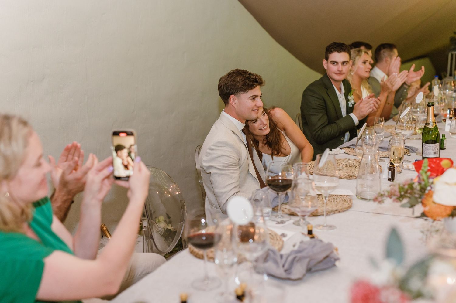 Wedding guests laughing and enjoying themselves during dinner at elegantly decorated reception tables.