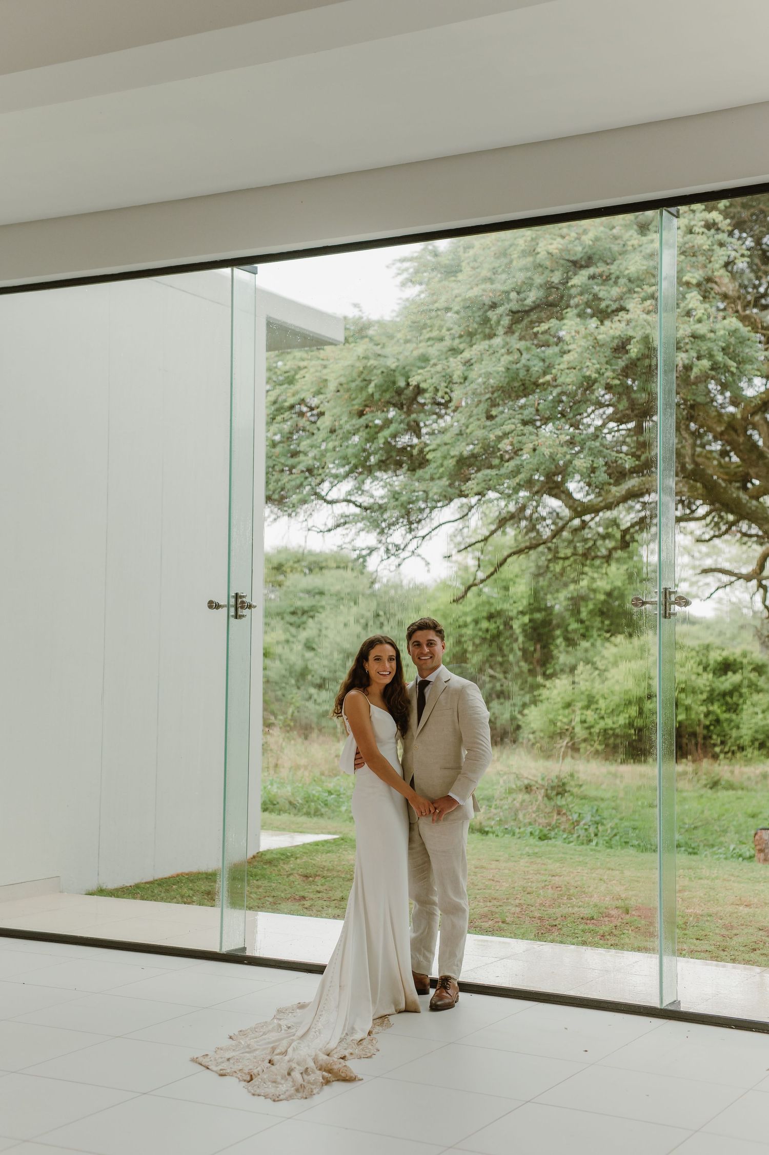 Elegant wedding photoshoot in a contemporary white space with floor-to-ceiling windows.