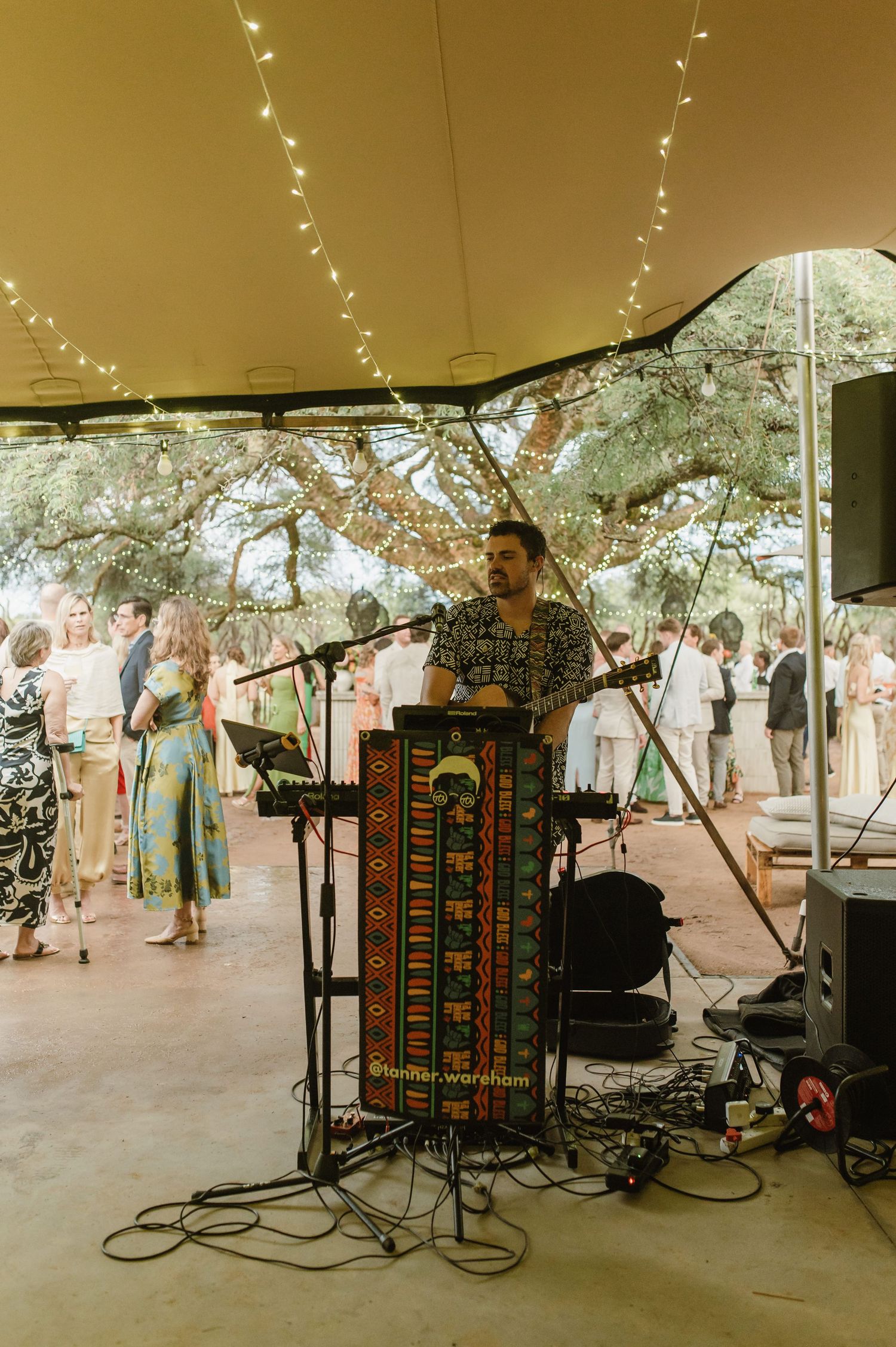Band equipment and speakers set up under a tent for outdoor wedding entertainment.