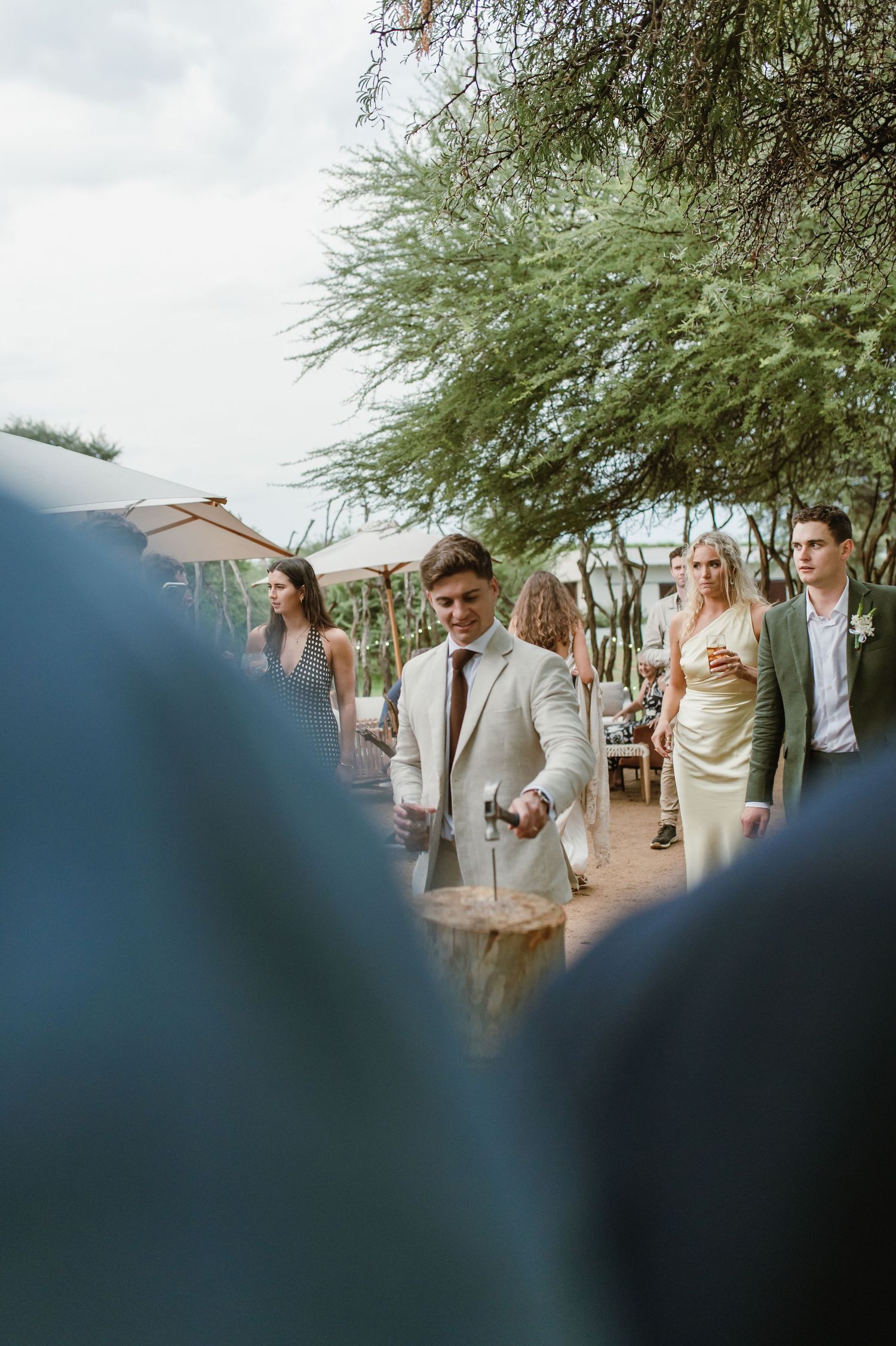Guests mingle at an outdoor wedding reception under desert trees.