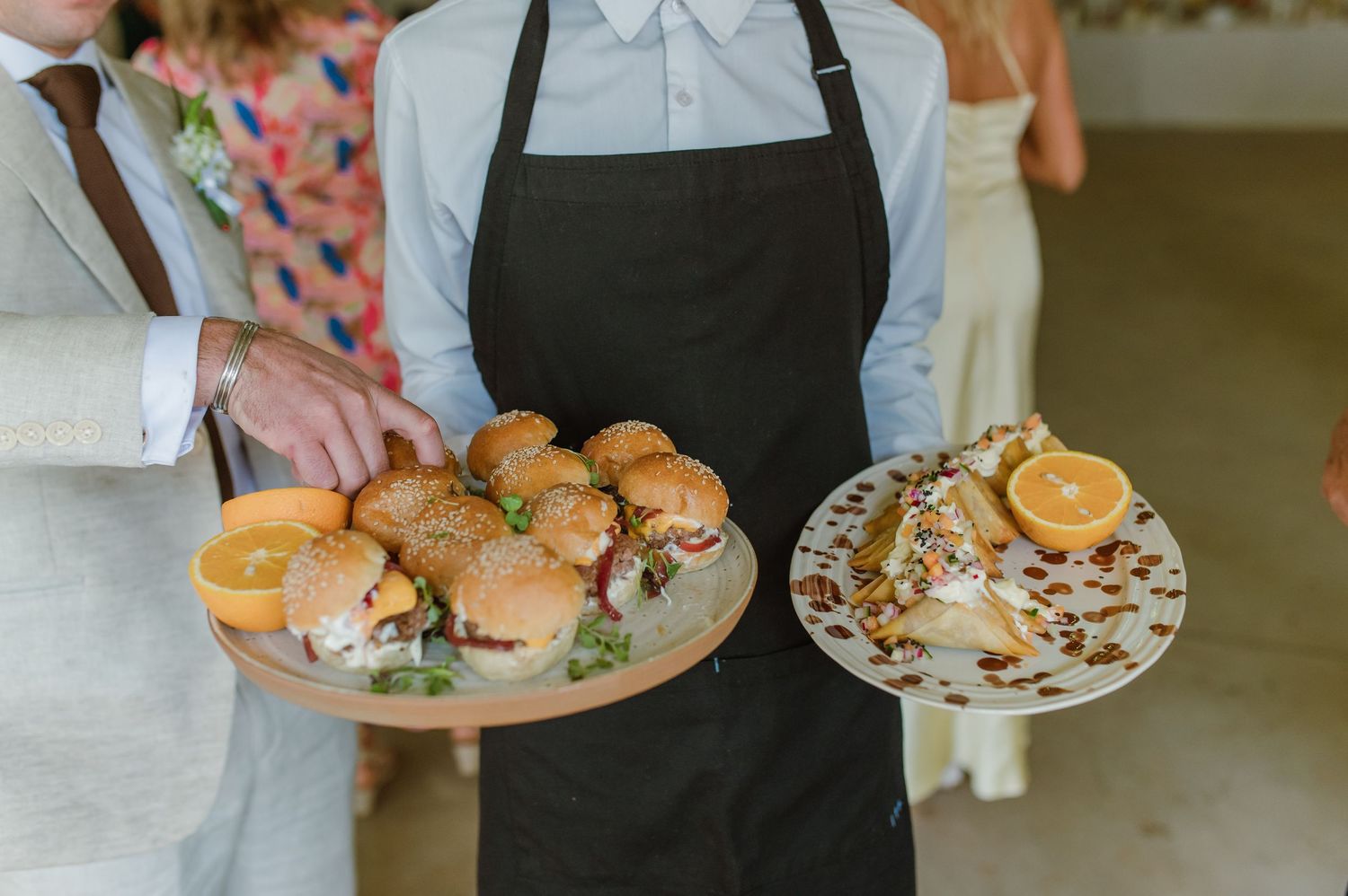 Catering staff serving appetizers and food plates at wedding reception.