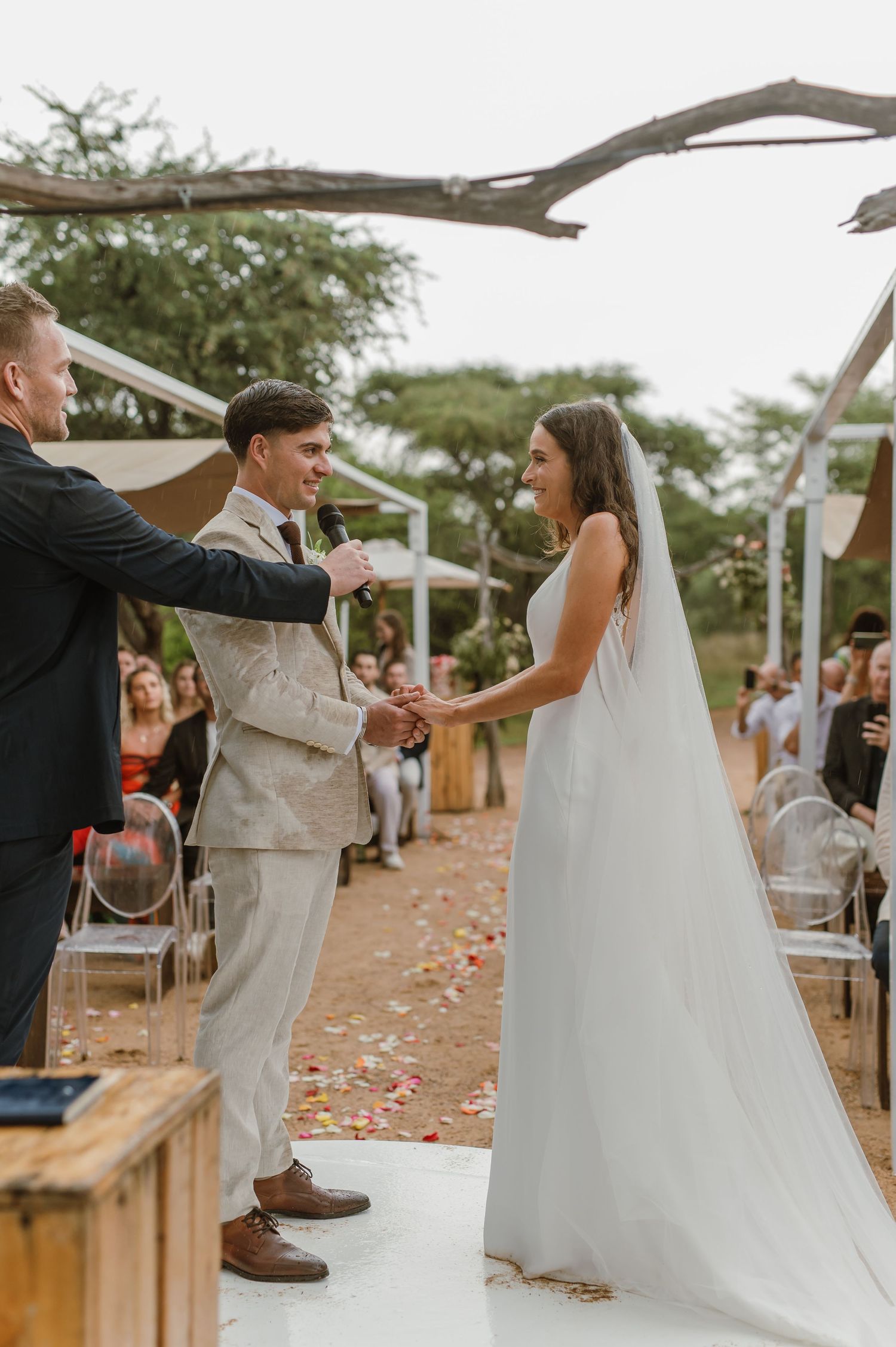 A couple performs a celebratory dance move on a circular white platform during their wedding ceremony.