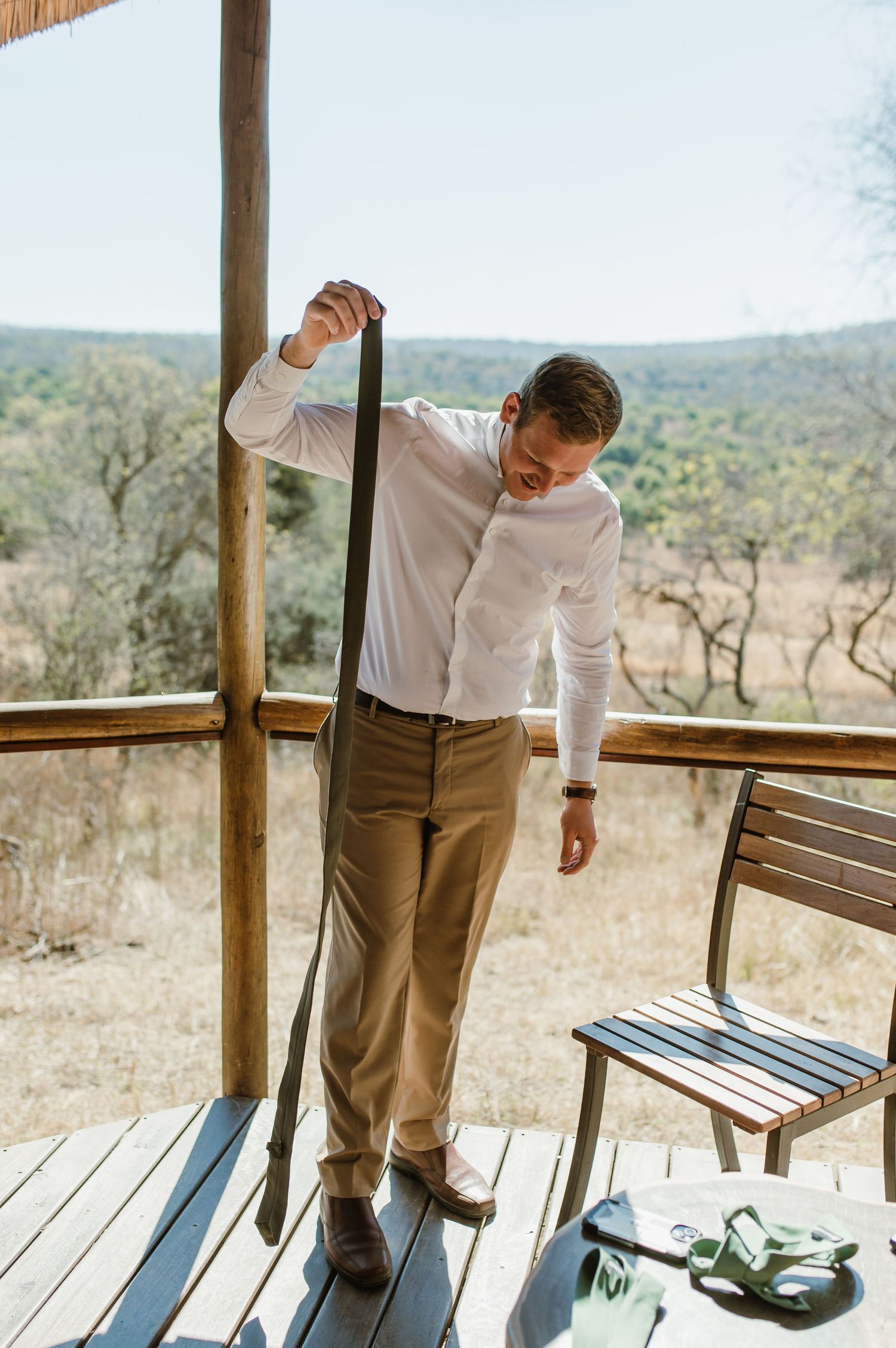 Person adjusting clothing while standing in rustic gazebo with scenic backdrop.
