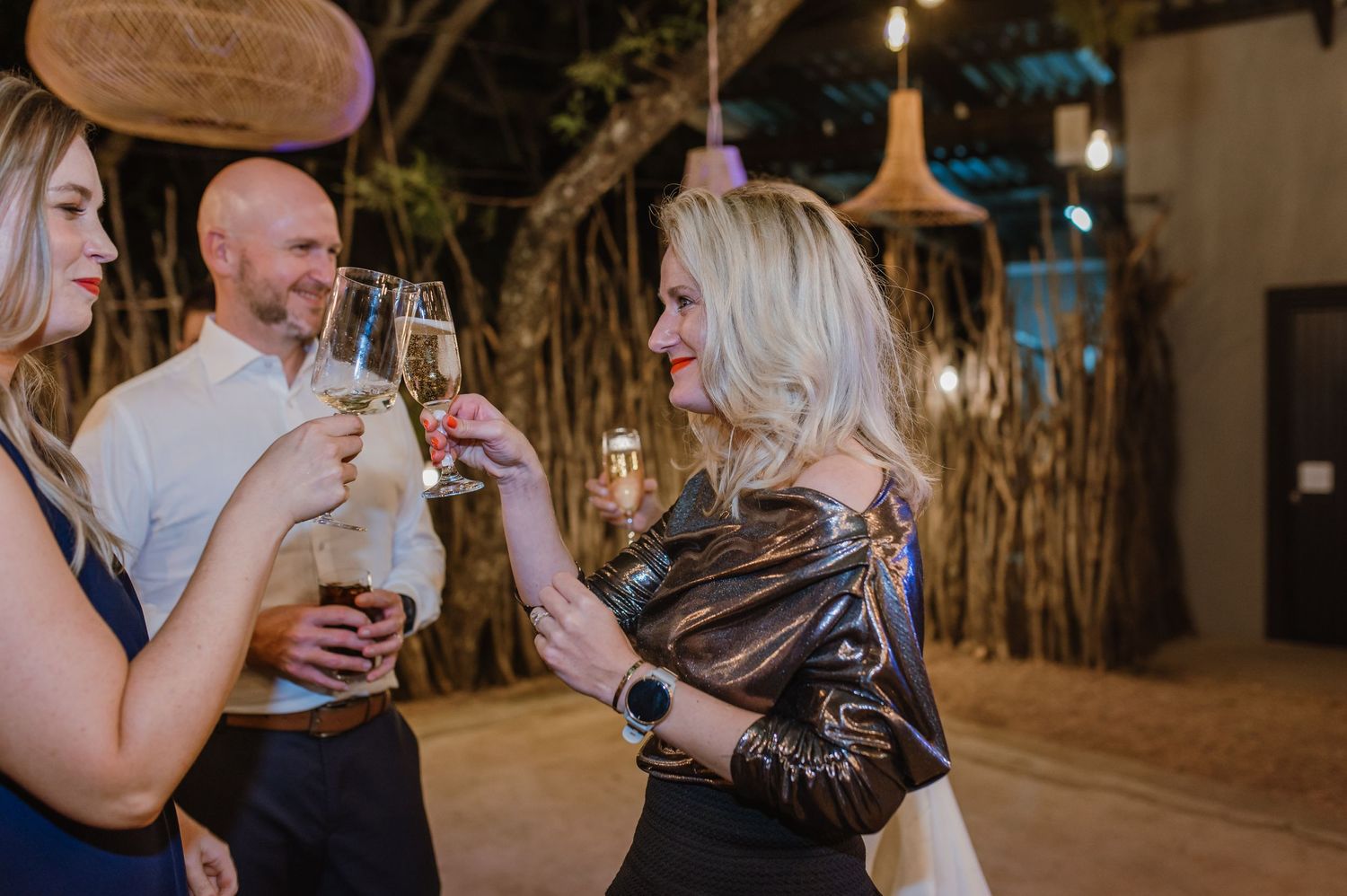 Wedding guests mingling and celebrating under warm lighting and rustic decor.
