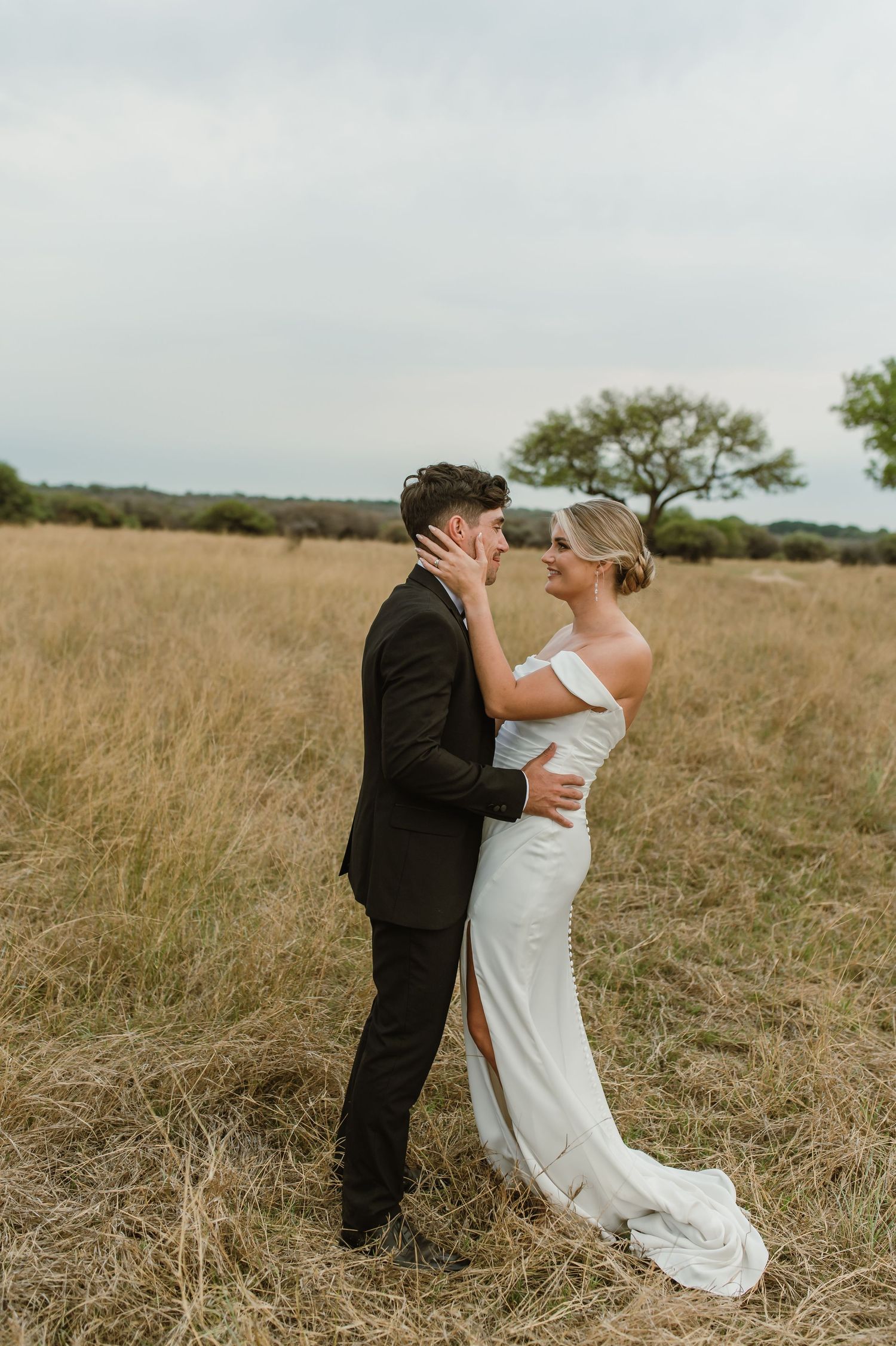 A romantic wedding moment captured in a serene field with natural lighting.