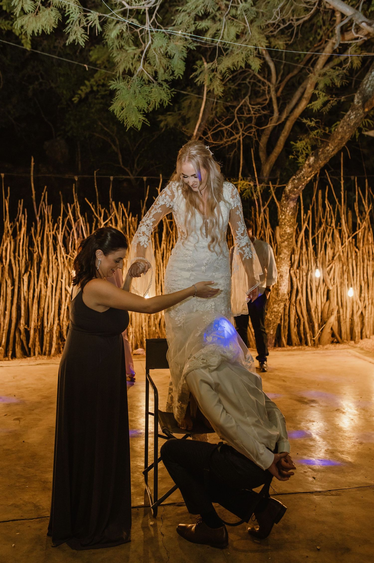 Wedding reception dance moment captured under rustic outdoor lighting and natural decor.
